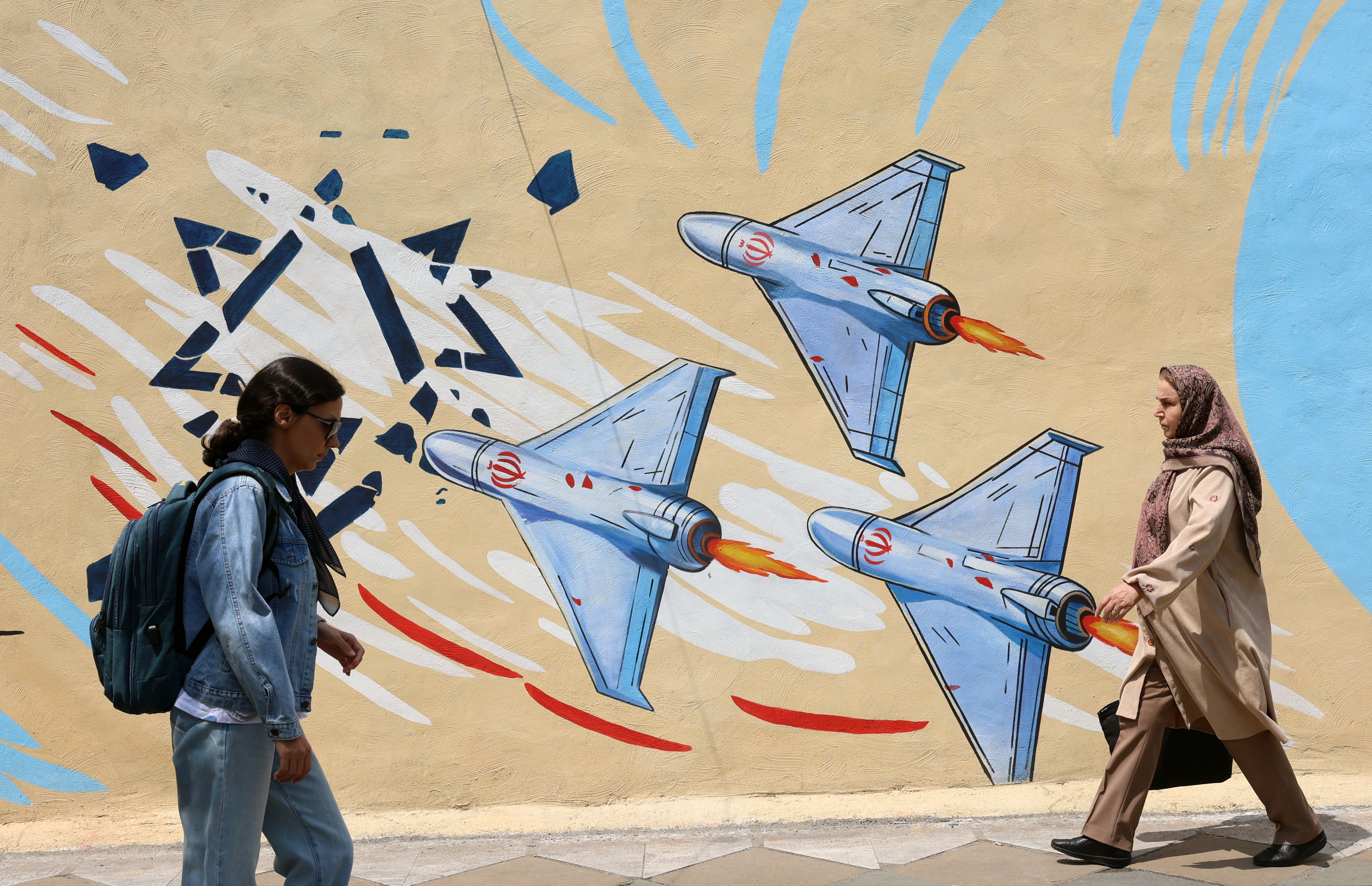 Iraníes caminan frente a un mural anti israelí en las calles de Teherán, Irán, este lunes 20 de abril. 