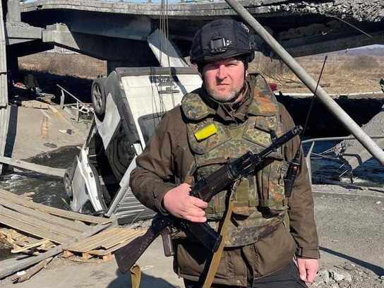 Oleksandr Markushyn posa em frente à ponte destruída naquela cidade para impedir o avanço das tropas russas.