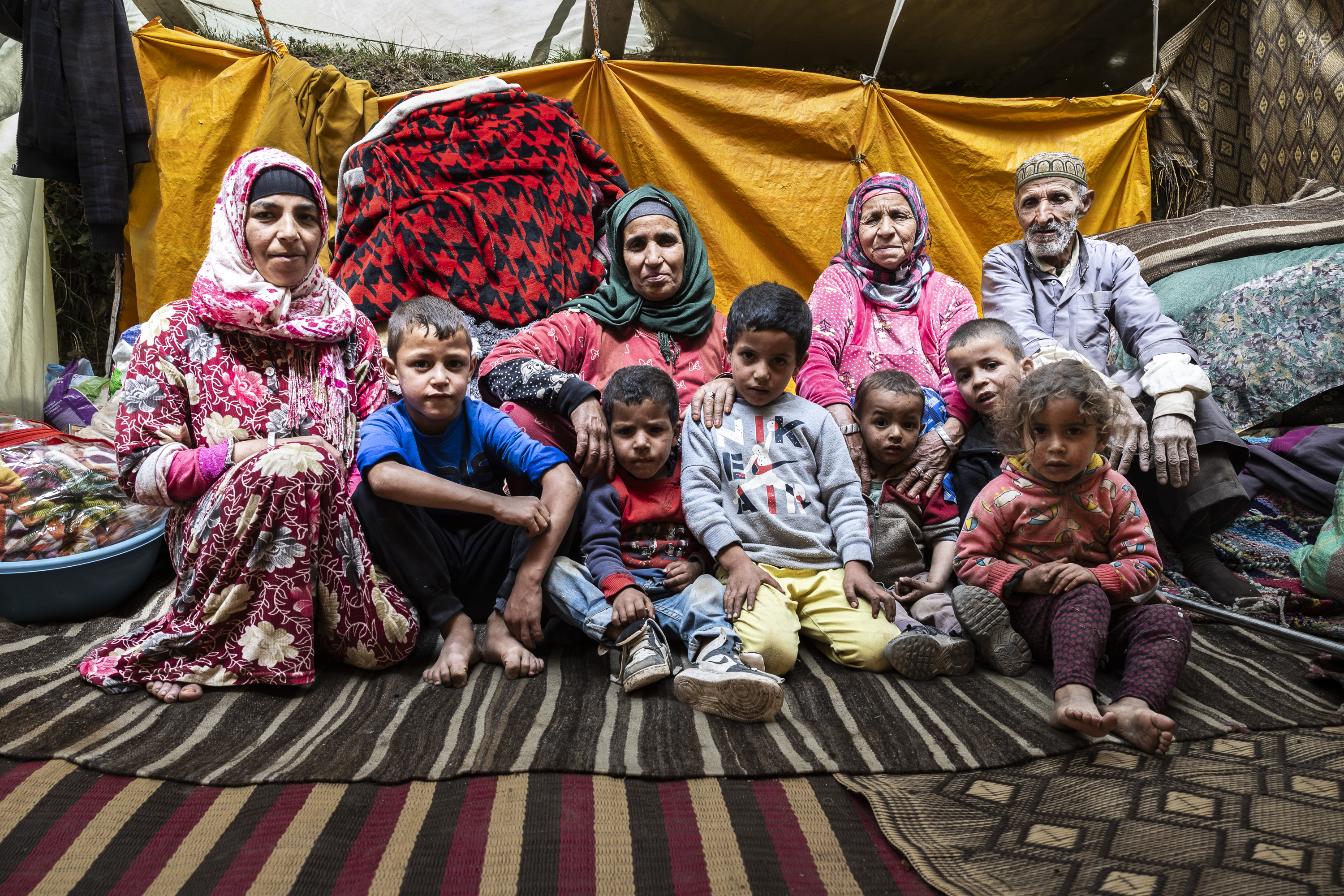 Da esquerda para a direita, Fatma Ait-Buri, Zahara Ait-Mjud, Aicha Ait-Buasis e Mohamed Ait-Mjud, 70 anos, a sua filha Aicha, juntamente com seis filhos da sua família, na tenda improvisada que se tornou a sua casa.