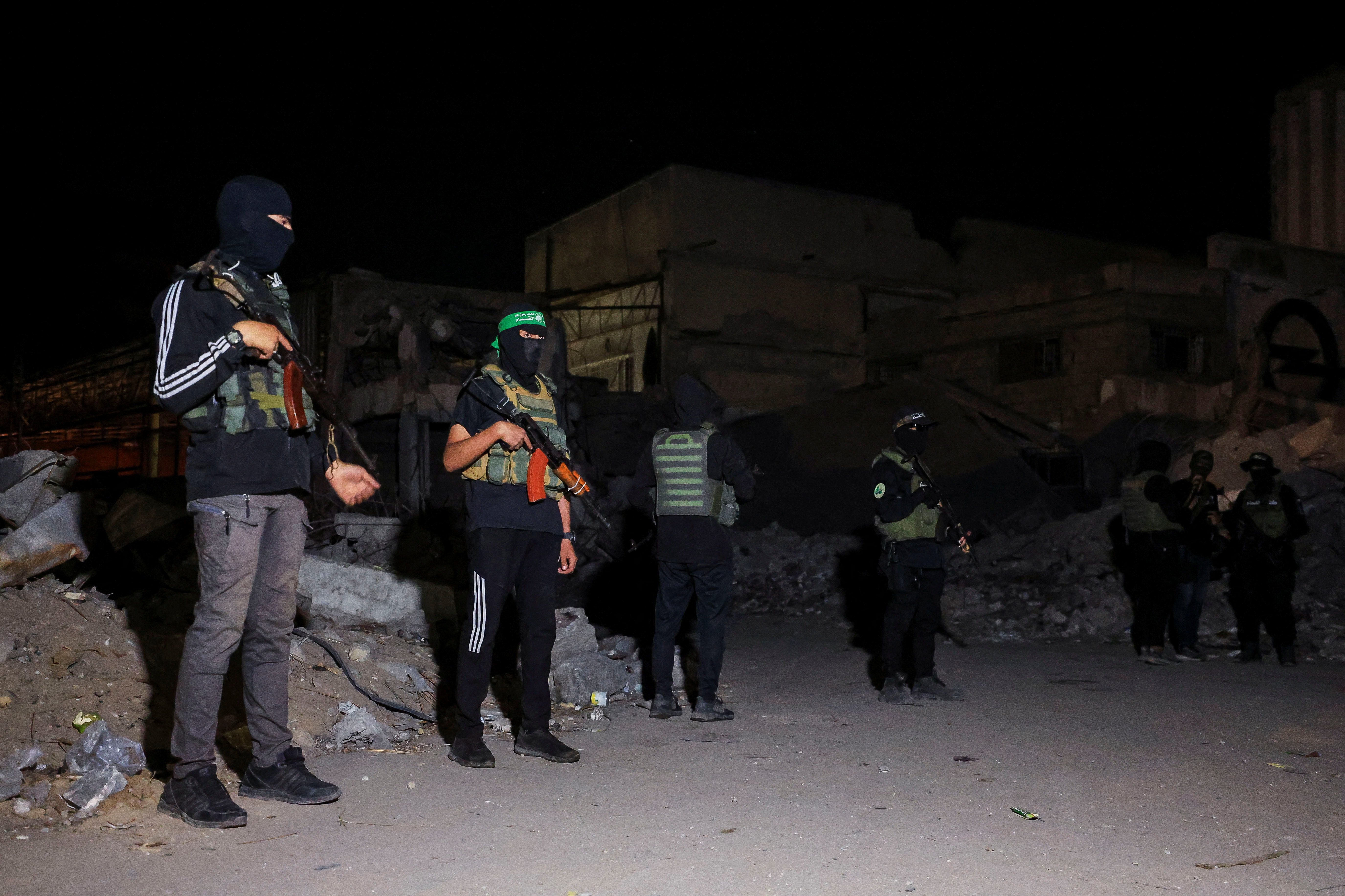 Hamas militants stand guard as Red Cross vehicles (not pictured) transport the bodies of hostages who were held in Gaza since the deadly October 7, 2023, attack, after they were handed over by Hamas militants as part of a ceasefire and a hostage-prisoner swap deal between Hamas and Israel, in Gaza City, October 15, 2025. REUTERS/Dawoud Abu Alkas