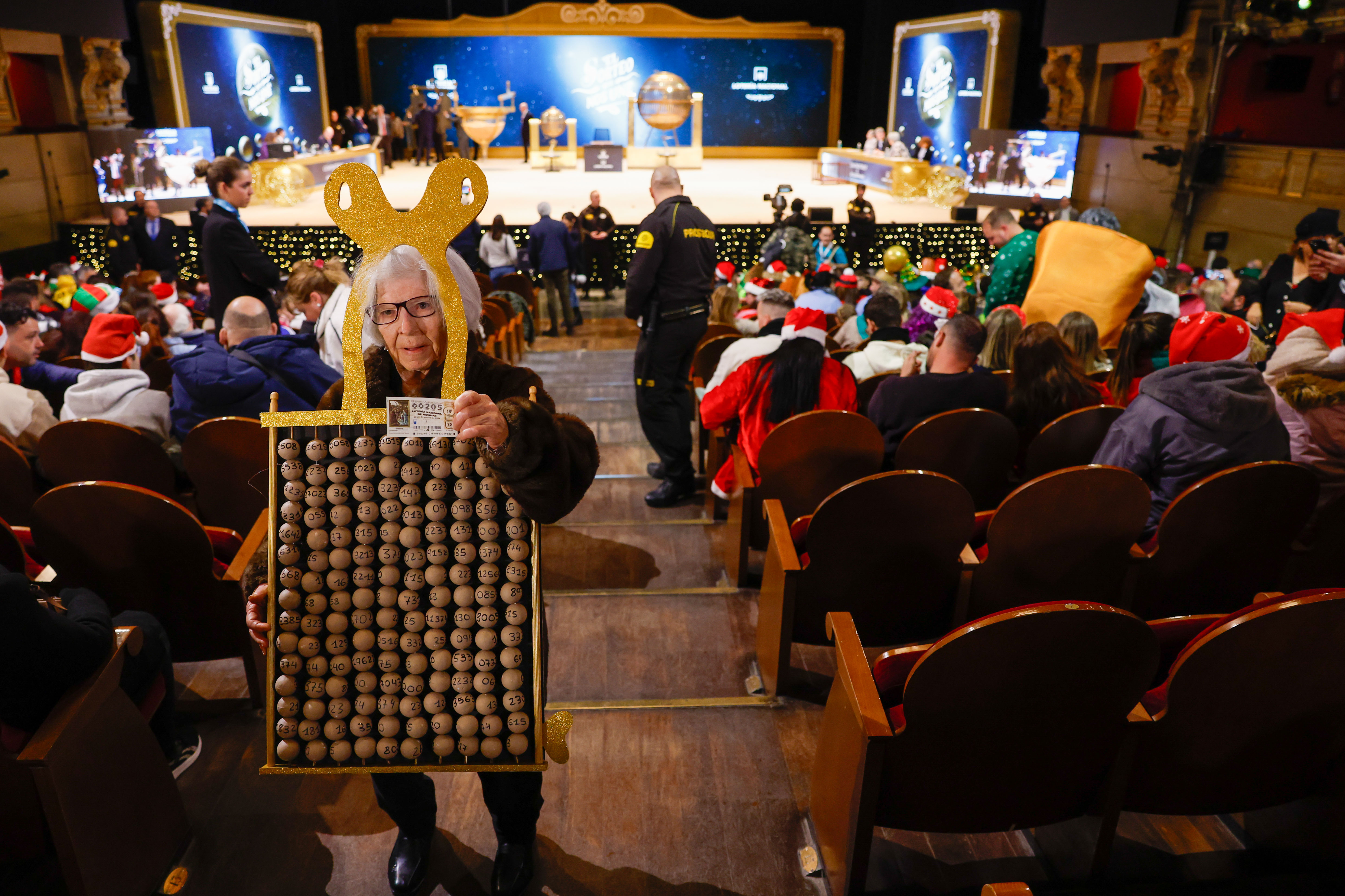 Asistentes aguardan el inicio del sorteo de la Lotería de Navidad este domingo en el Teatro Real, en Madrid. 