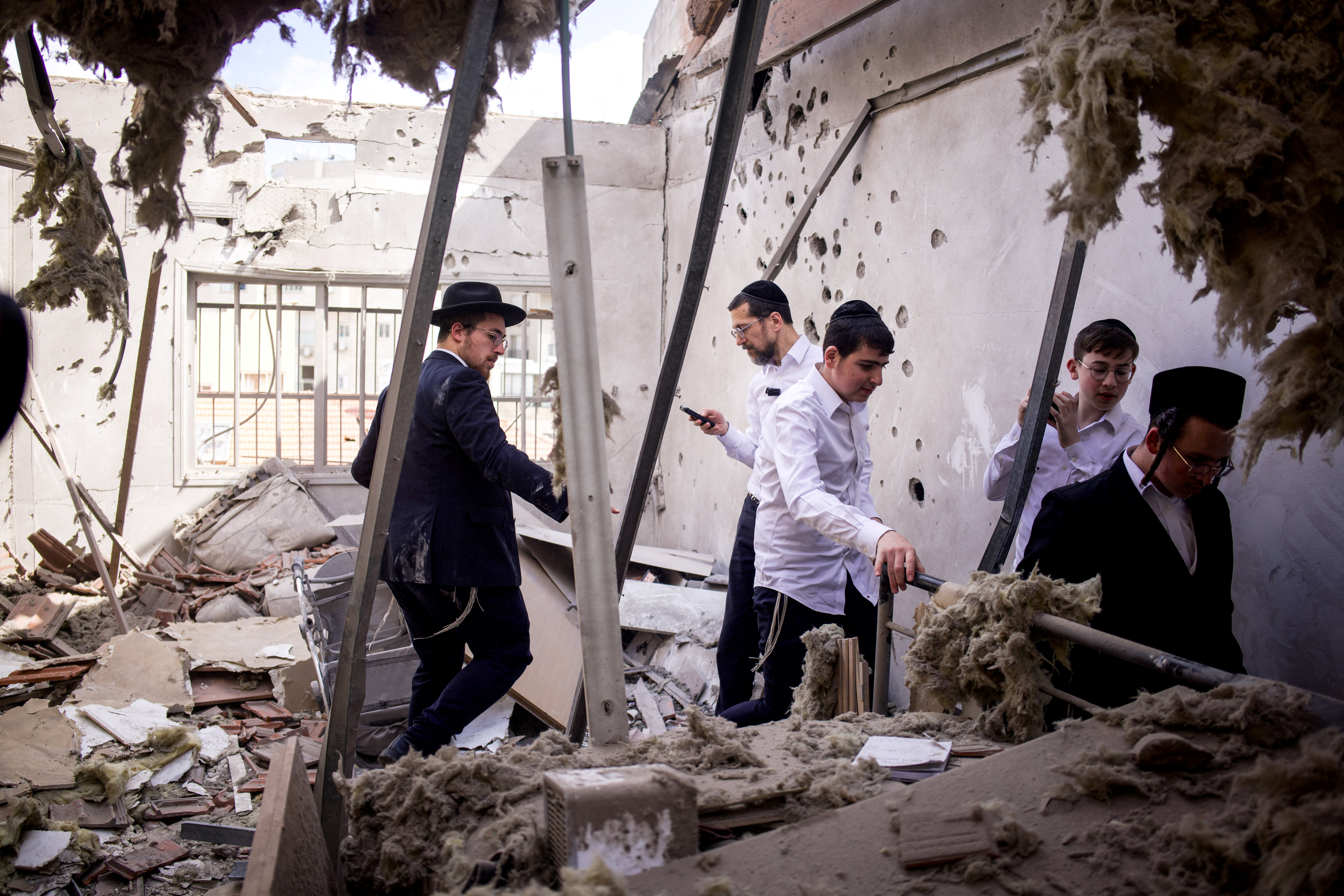Judíos ultraortodoxos revisan un edificio dañado tras un bombardeo iraní, este martes 31 de marzo.