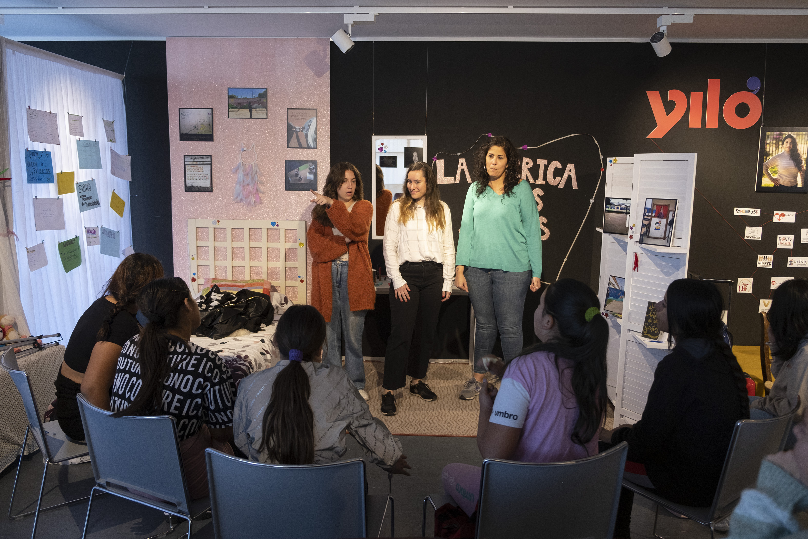 Niñas gitanas e integrantes del proyecto [J]itana, delante de un cartel de Yiló.