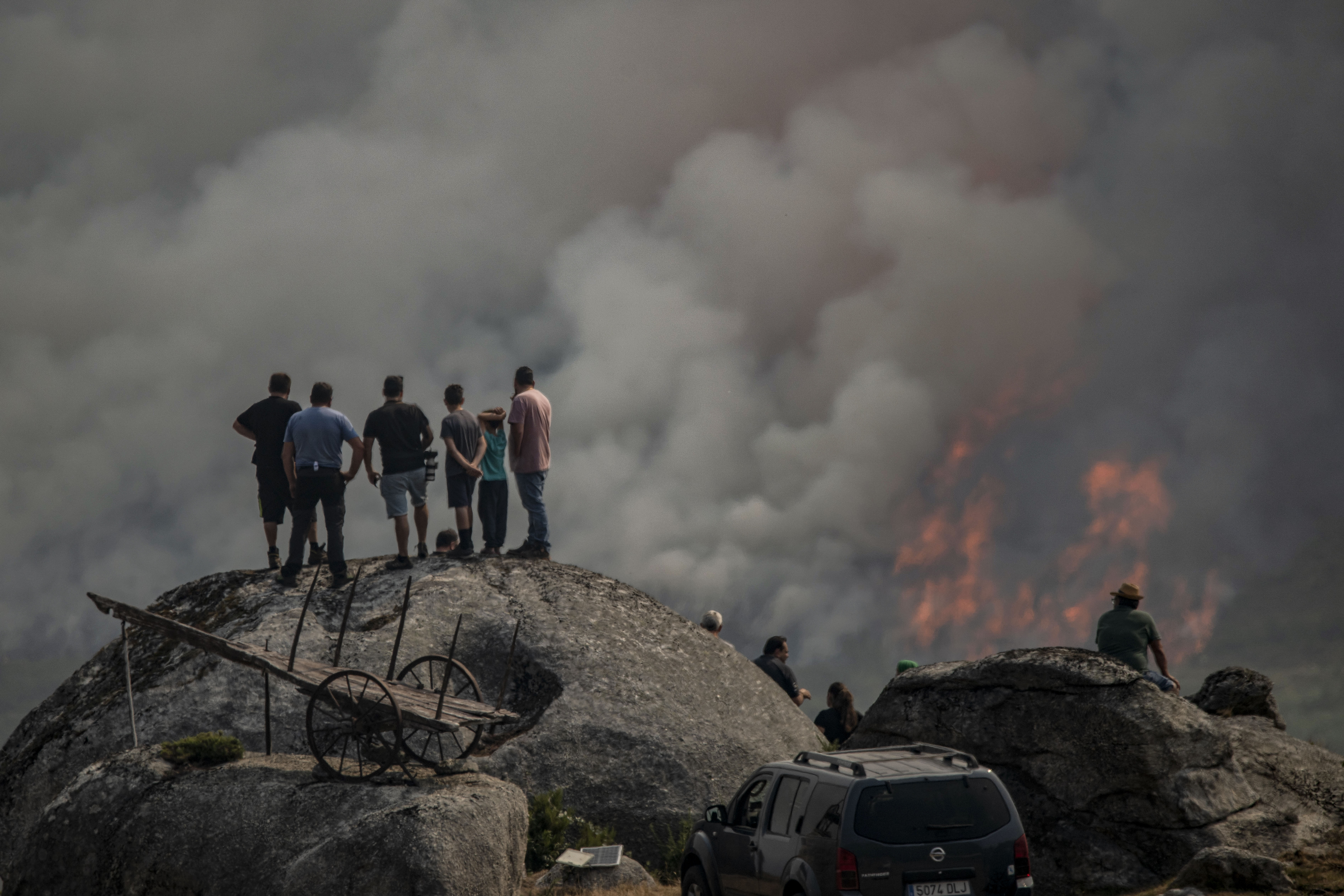 Varias personas observan el incendio forestal declarado ayer en Avión (Ourense), este lunes 25 de agosto.