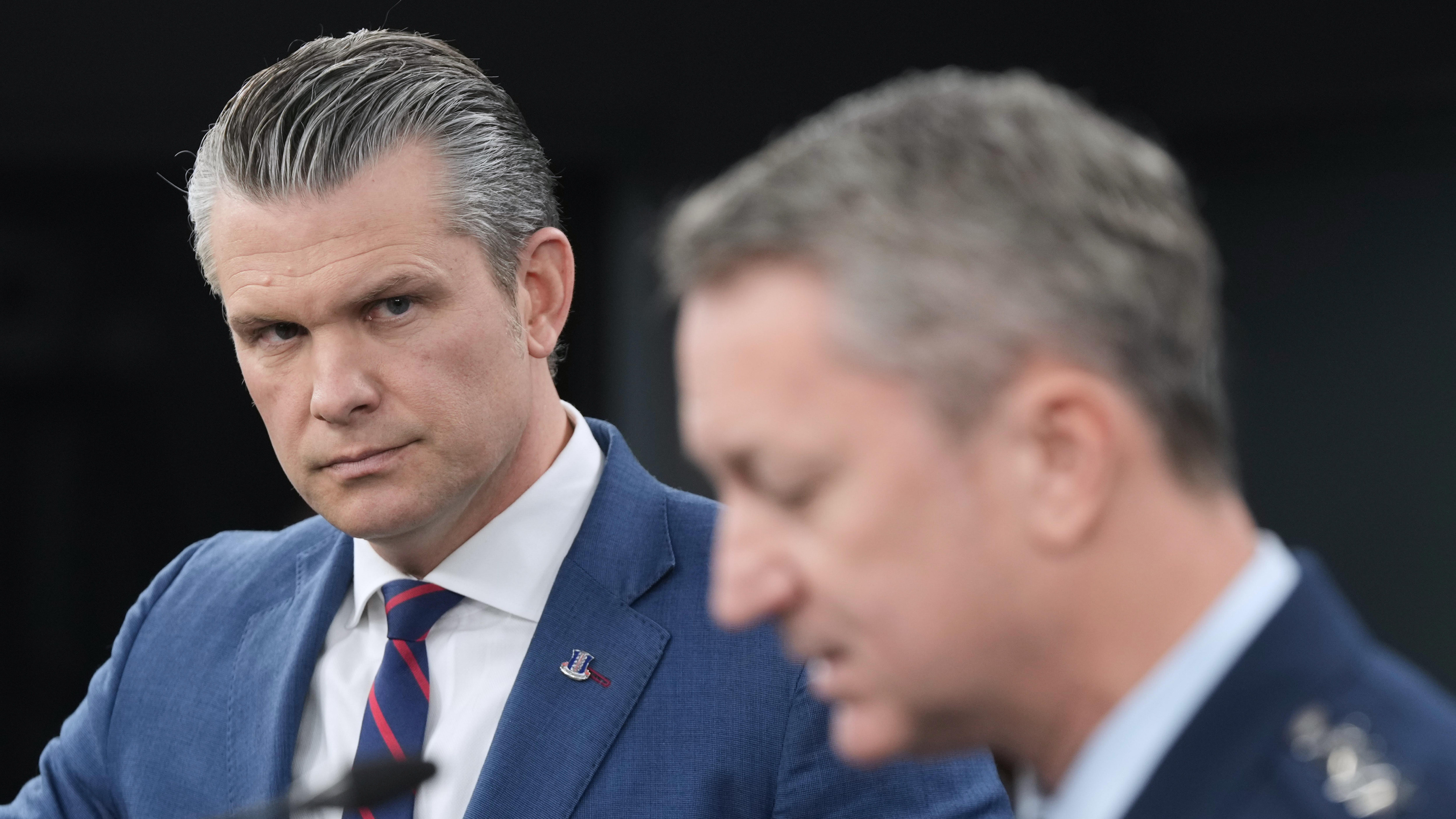 Defense Secretary Pete Hegseth listens to Chairman of the Joint Chiefs of Staff Gen. Dan Caine, during a press briefing at the Pentagon, Monday, March 2, 2026, in Washington. (AP Photo/Mark Schiefelbein)