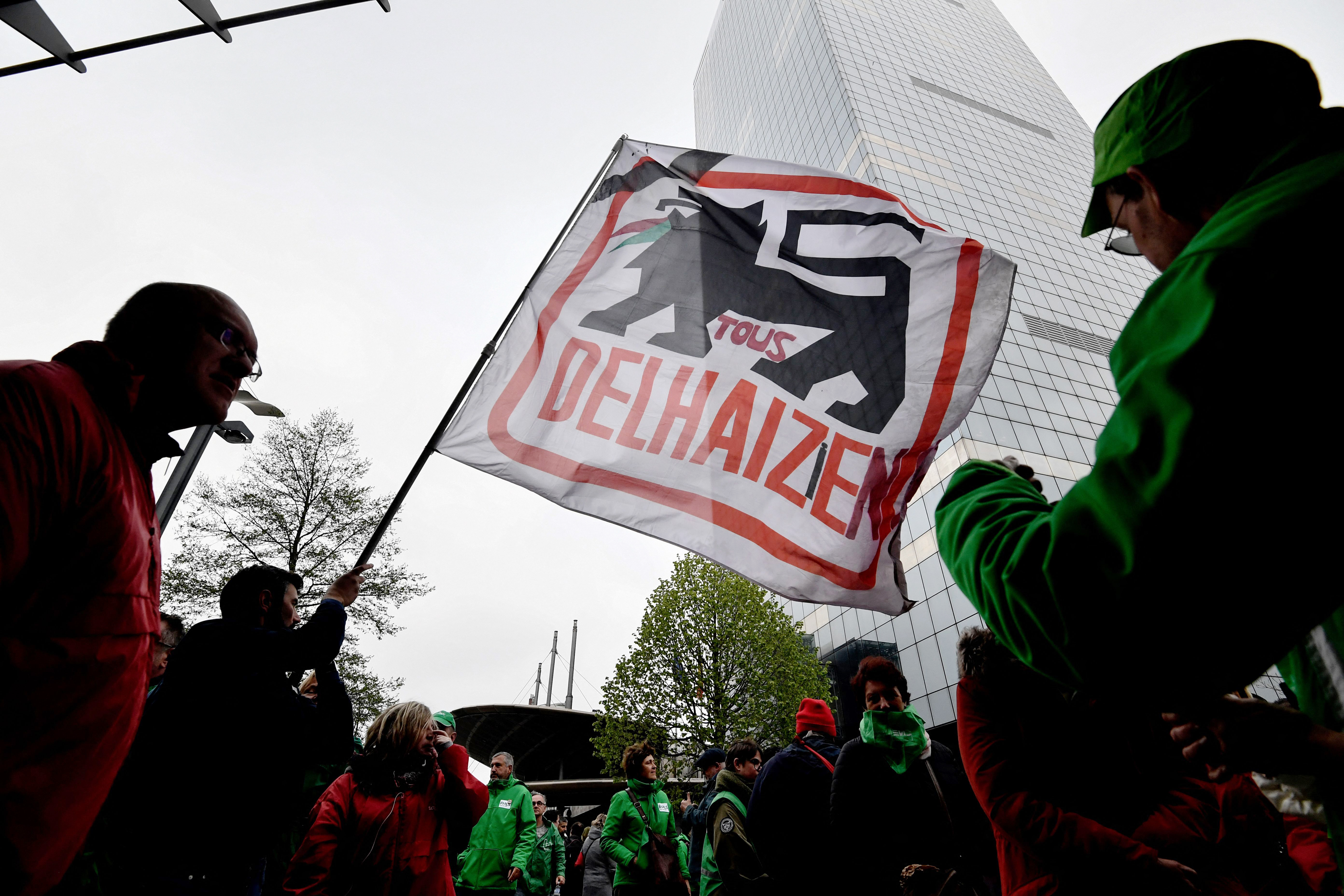Protestors hold a flag of the Belgium supermarket group Delhaize during demonstrations against 'social dumping' in Brussels on April 17, 2023. (Photo by JOHN THYS / AFP) (Photo by JOHN THYS/AFP via Getty Images)