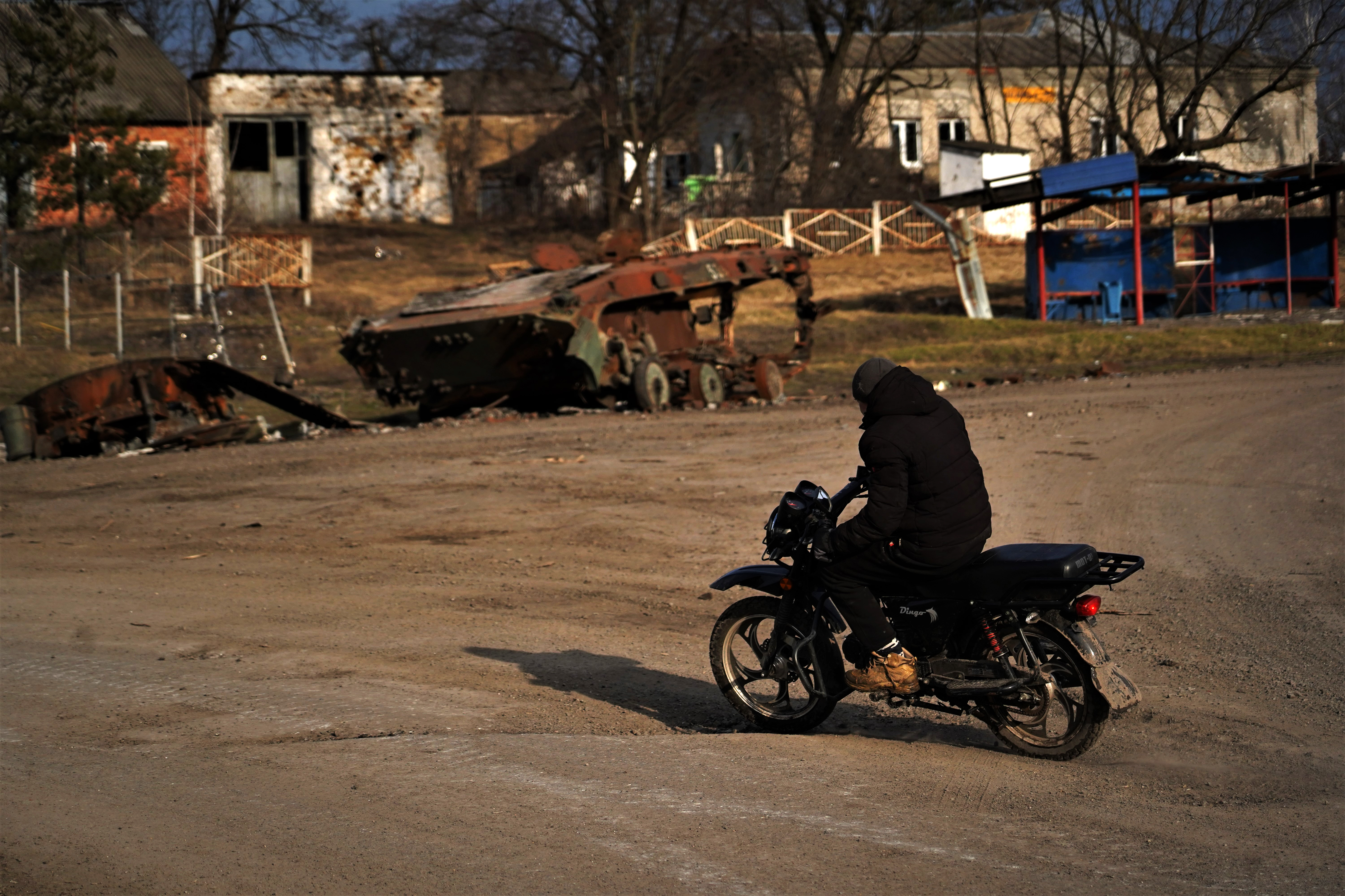 Um homem com uma motocicleta atravessa a cidade quase deserta de Petropavlivka.