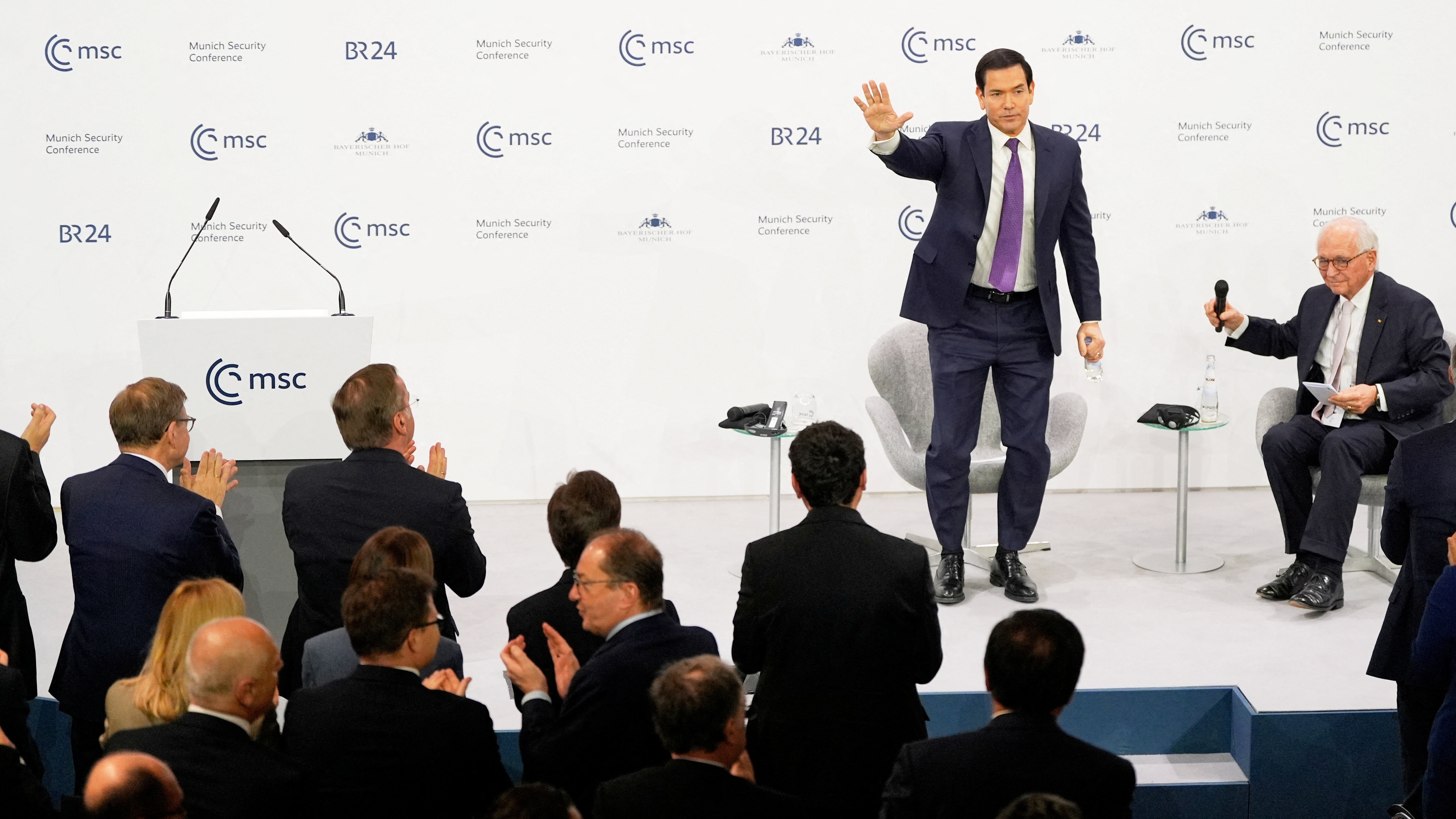 U.S. Secretary of State Marco Rubio waves, next to Chairman of the Munich Security Conference Wolfgang Ischinger, as he gets a standing ovation after his speech at the Munich Security Conference in Munich, Germany, Saturday, Feb. 14, 2026.     Alex Brandon/Pool via REUTERS