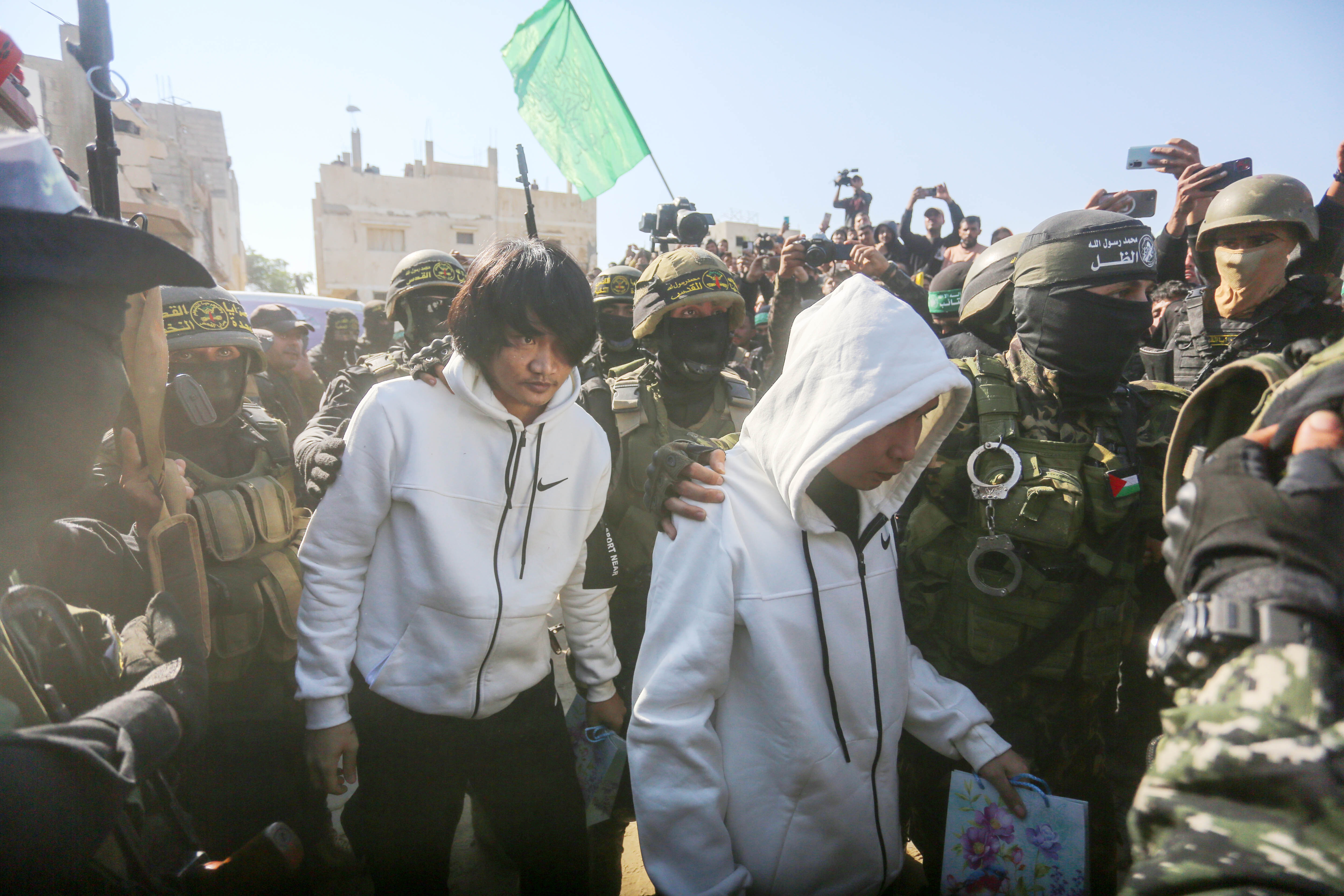 Dos de los cinco rehenes tailandeses caminan en medio de milicianos de Hamás y la Yihad Islámica para ser liberados, este jueves 30 de enero de 2025.