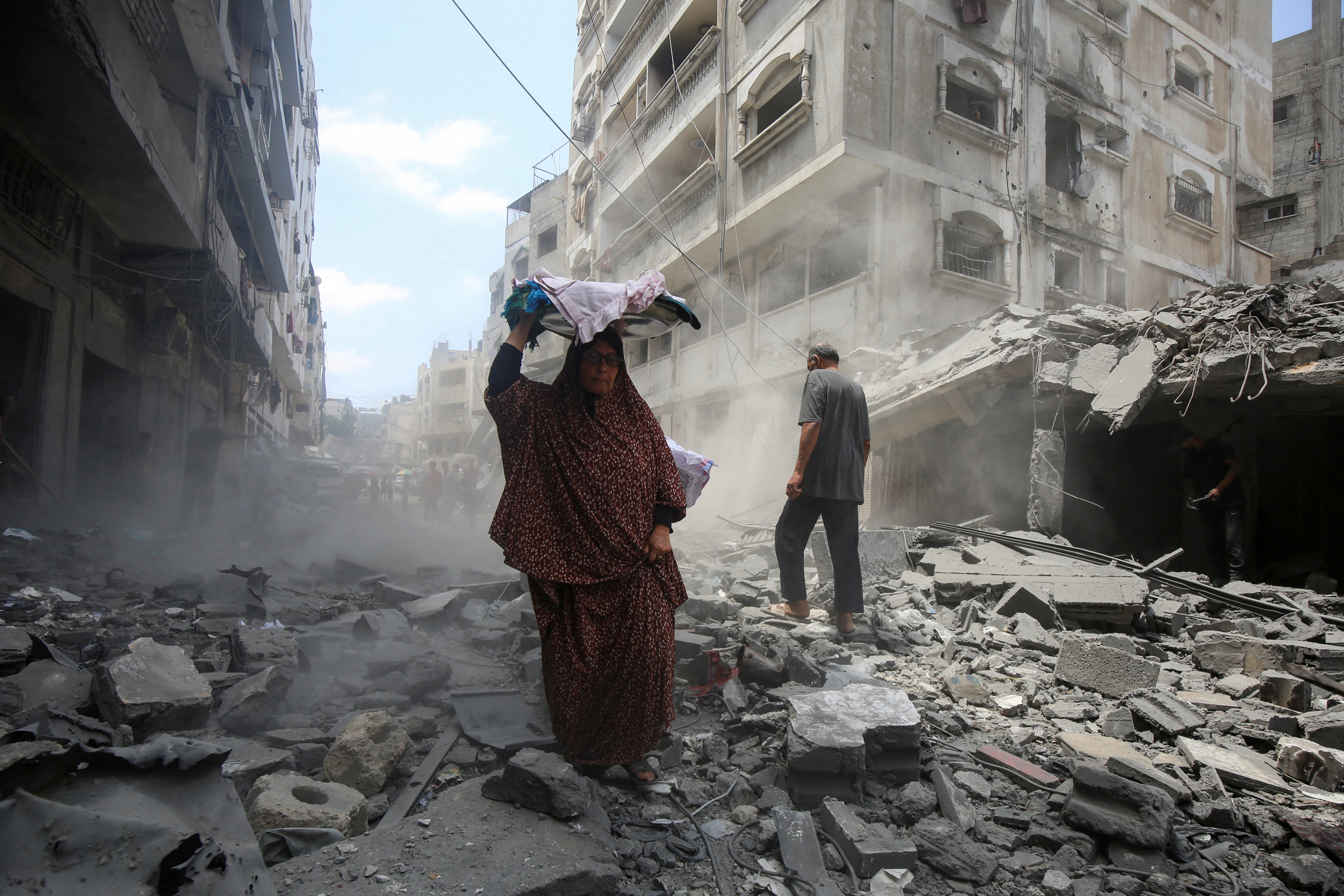 Una mujer camina sobre los escombros causados por un ataque israelí en Ciudad de Gaza, este viernes 8  de agosto de 2025.