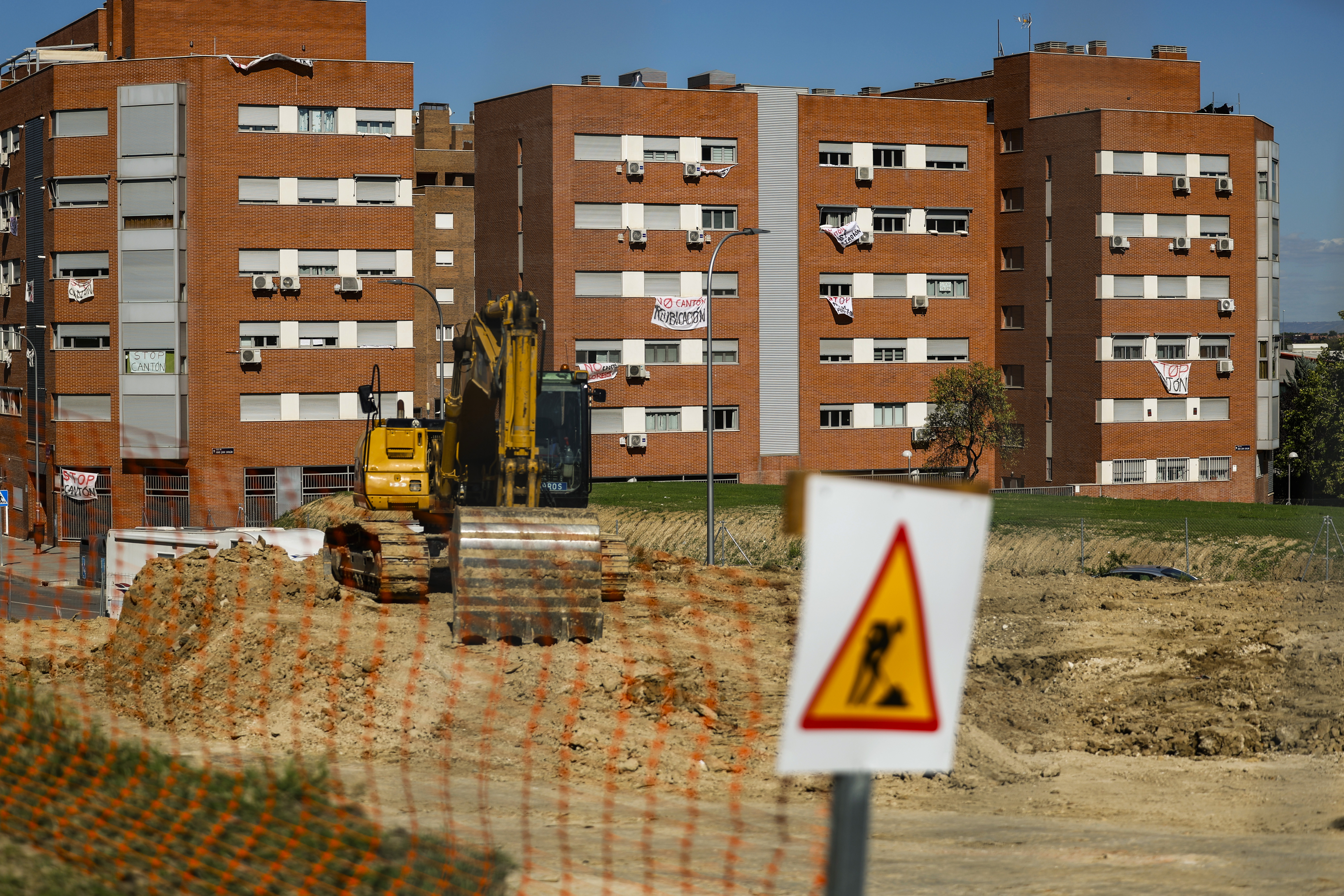 Una retroexcavadora aparcada, el 22 de septiembre, en la parcela donde se construirá el cantón auxiliar de Vicálvaro. Al fondo, los vecinos han colgado carteles y lonas con mensajes contra la obra.