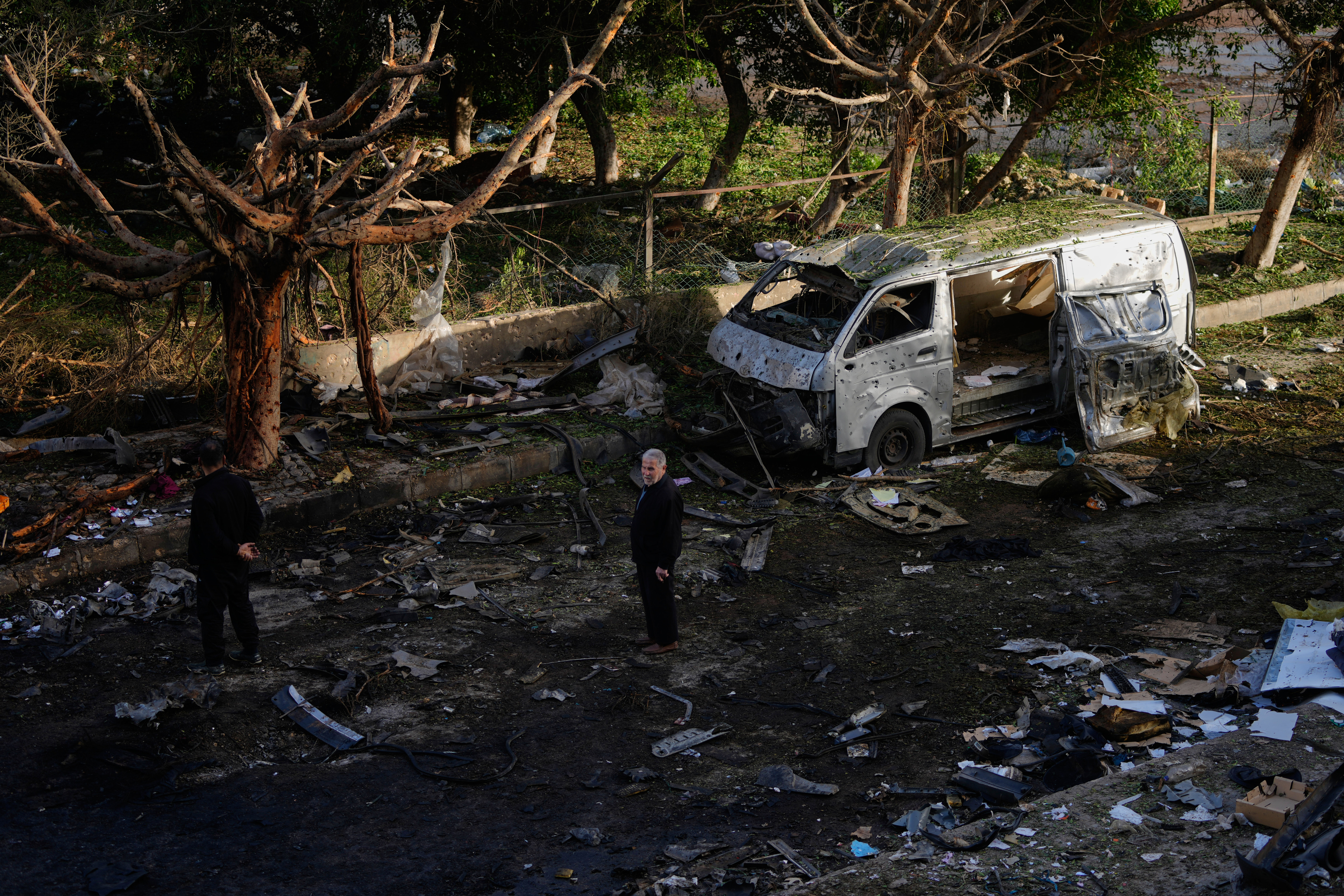 Personas paradas cerca un vehículo destruido en un bombardeo israelí en Beirut, Líbano, este miércoles 1 de abril.