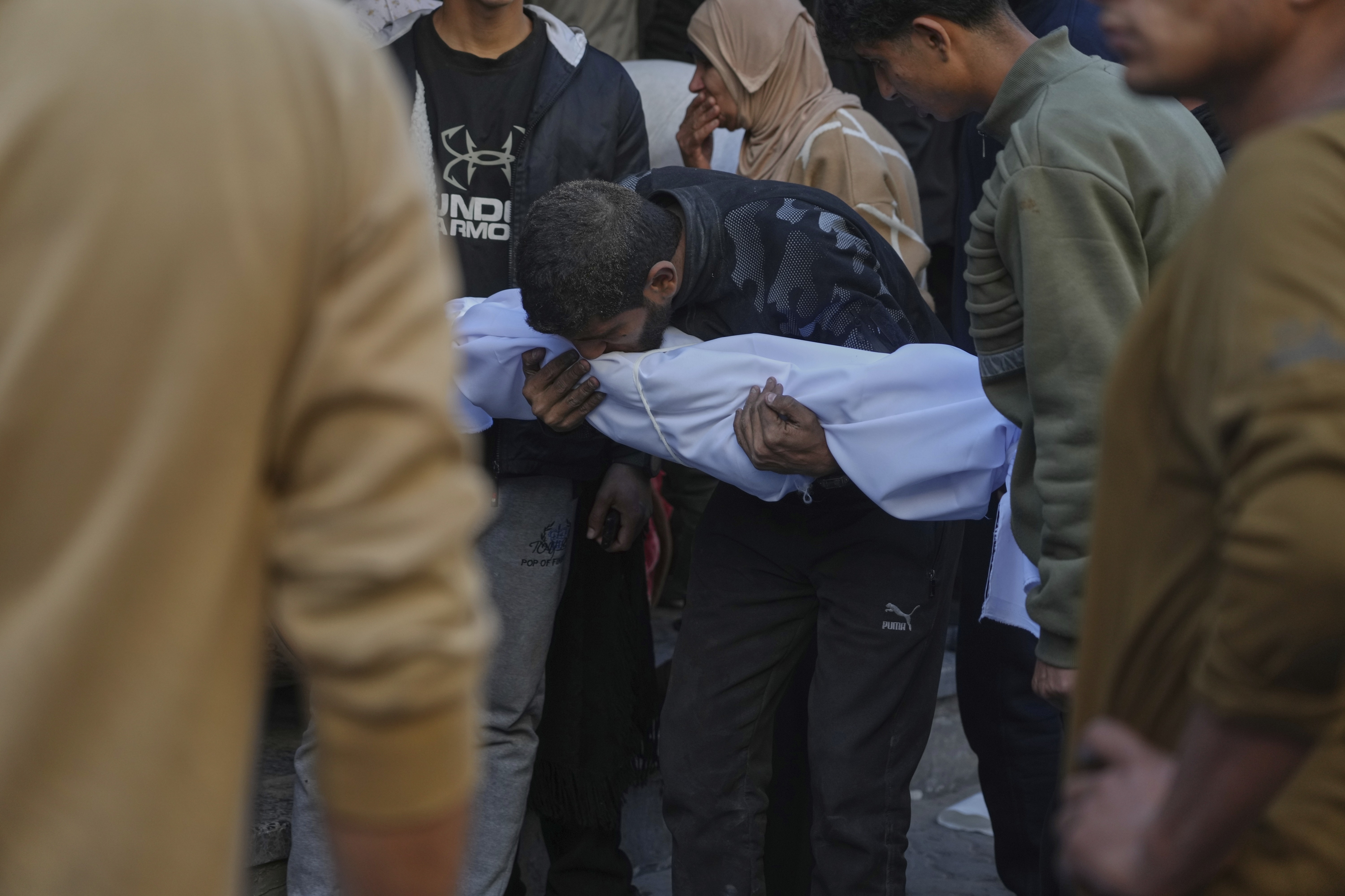 Un hombre lleva el cadáver de un menor fallecido por los ataques de Israel, en Ciudad de Gaza.