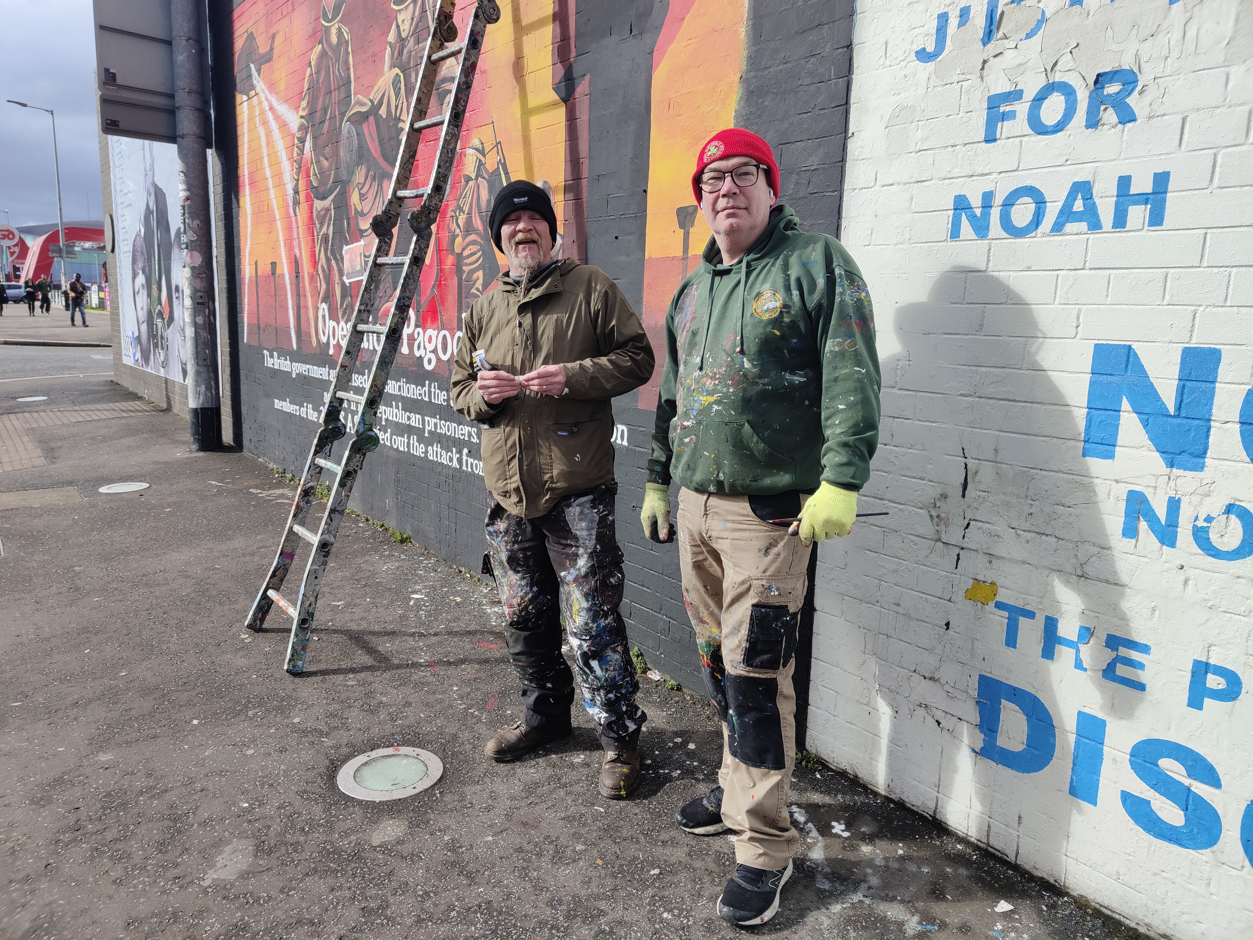 Dois membros expressos do IRA, quinta-feira passada, ao pé dos murais que pintaram em Falls Road (Belfast).