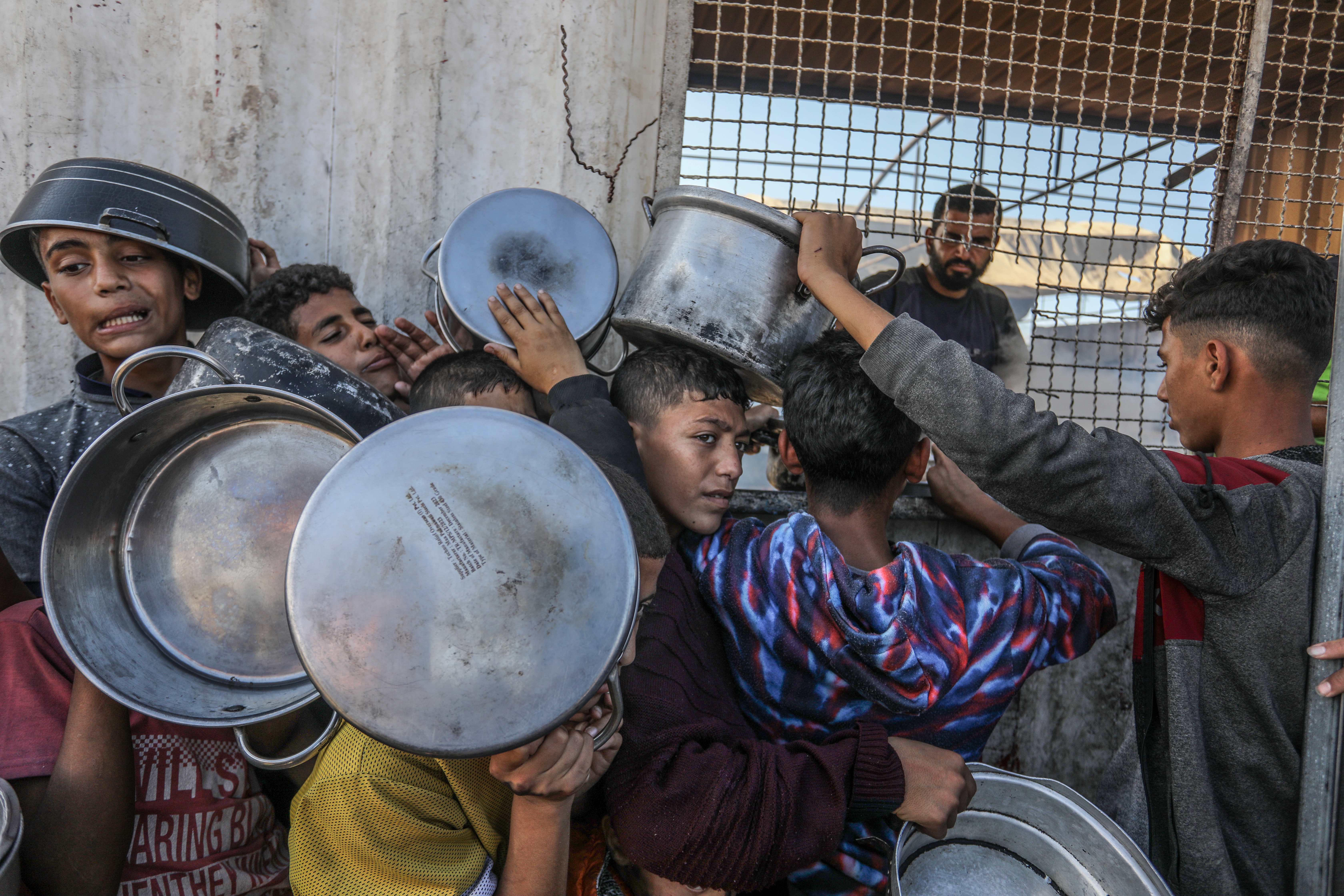 Un grupo de jóvenes se forma para recibía alimentos del Programa Mundial de Alimentos y la Agencia de Naciones Unidas para los Refugiados Palestinos en Jan Yunis, en el sur de la franja de Gaza, el 16 de noviembre de 2024