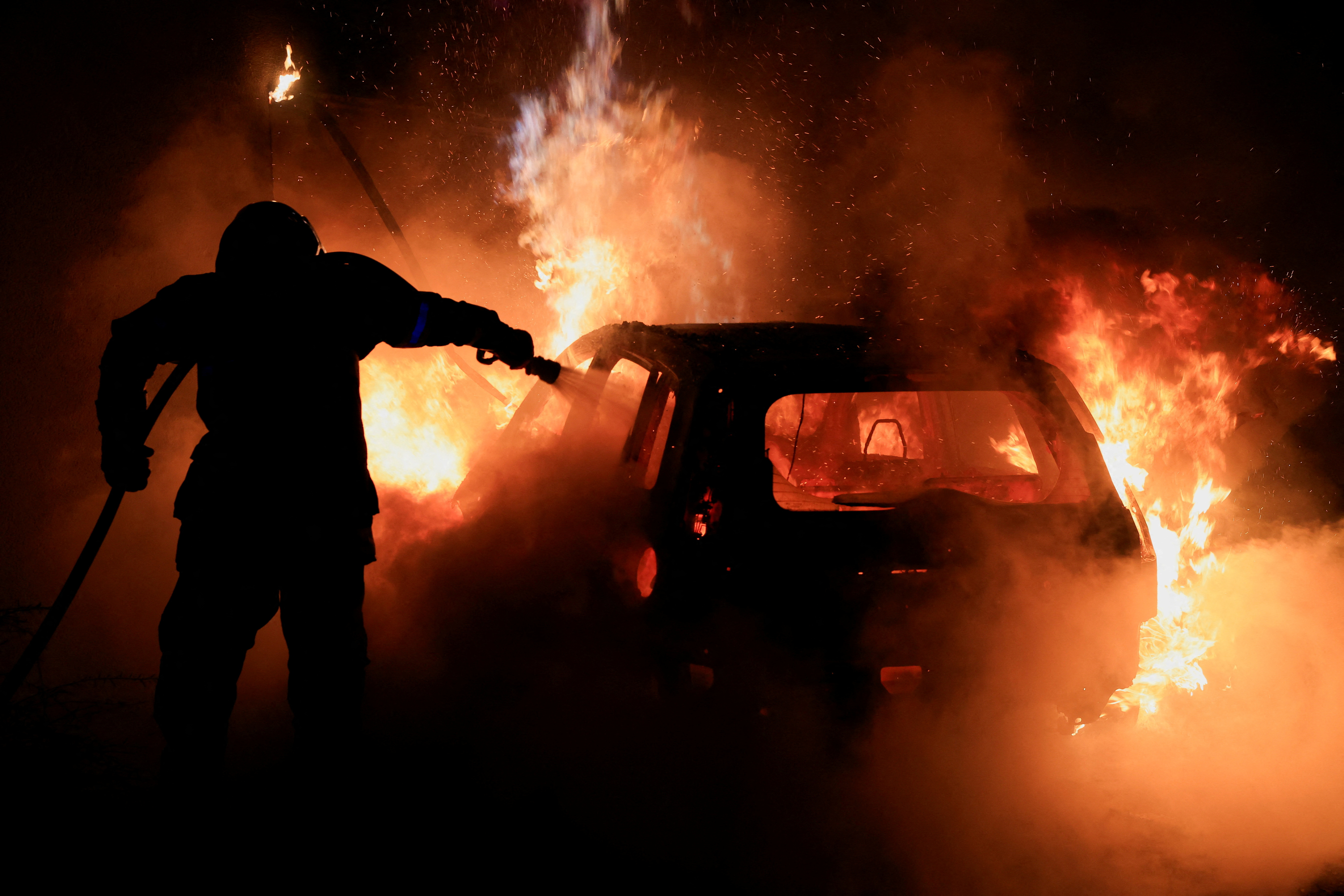 Um bombeiro apaga as chamas de um carro durante os protestos em Nanterre, na manhã passada.  