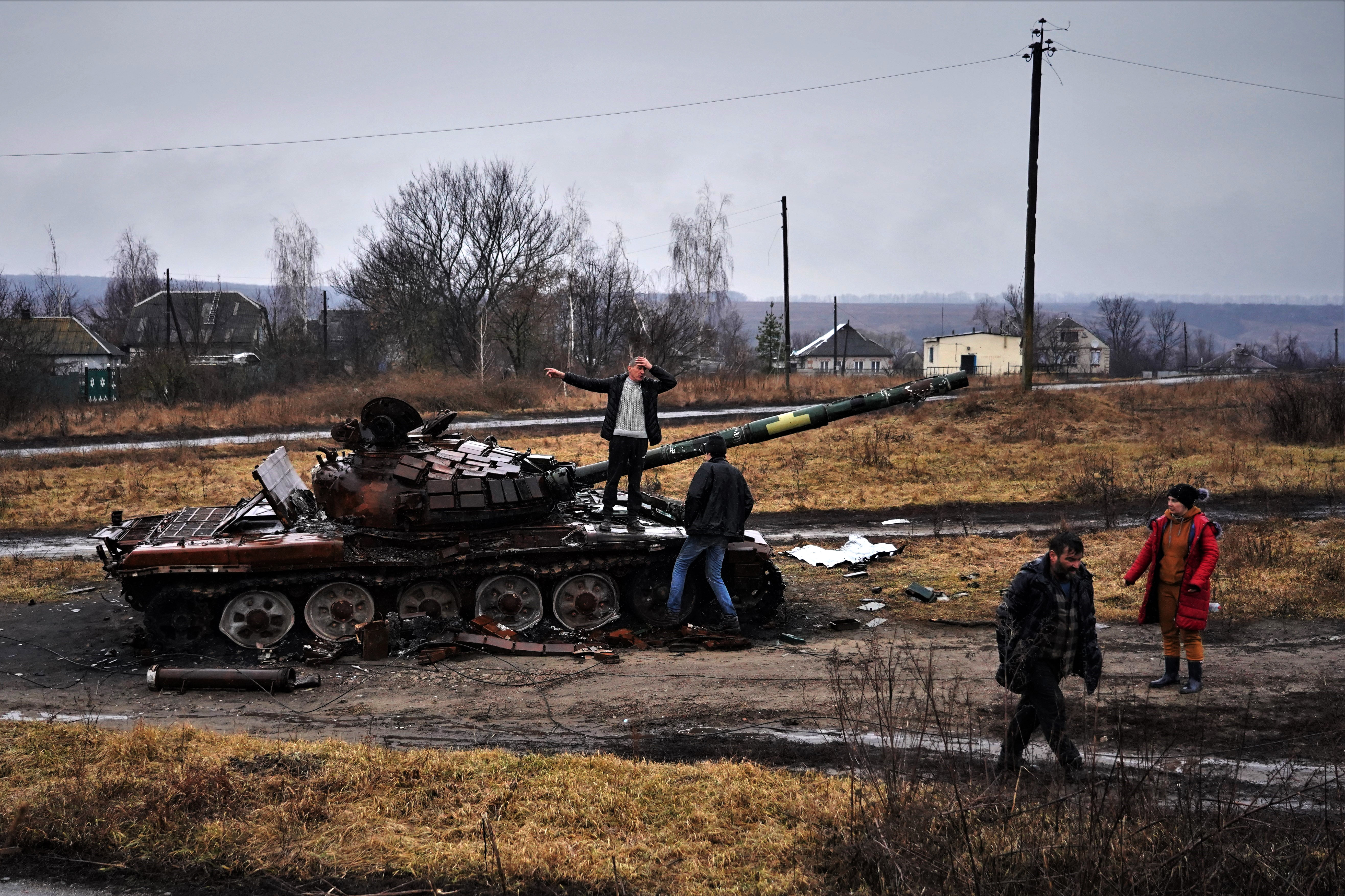Moradores de Tsupivka, na região de Kharkov, ao lado do tanque do exército ucraniano que ficou em frente a suas casas após a batalha para libertar a cidade da ocupação russa.