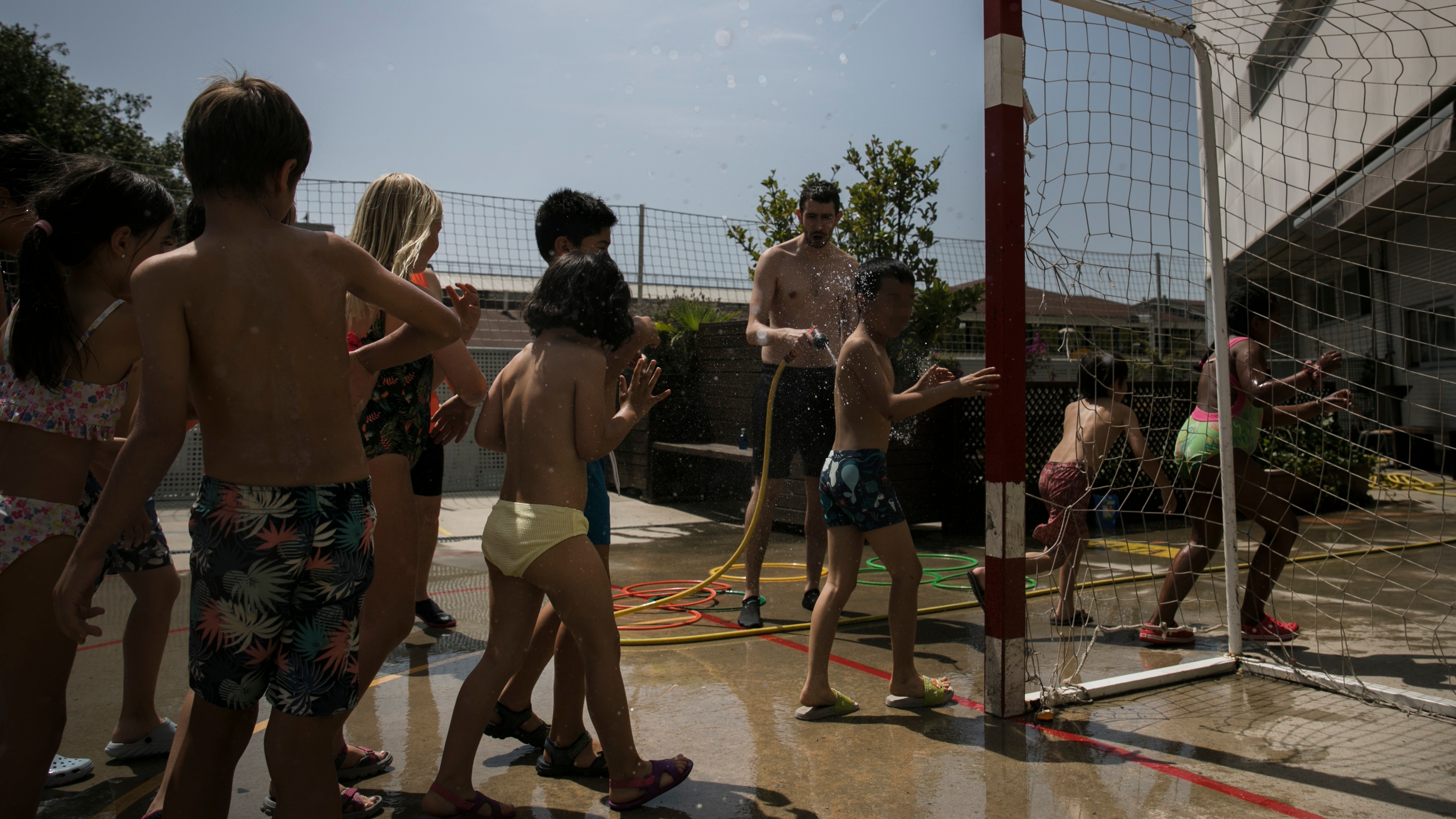 Alumnos de la escuela Fort Pienc de Barcelona jugaban con agua en el patio durante la ola de calor. 