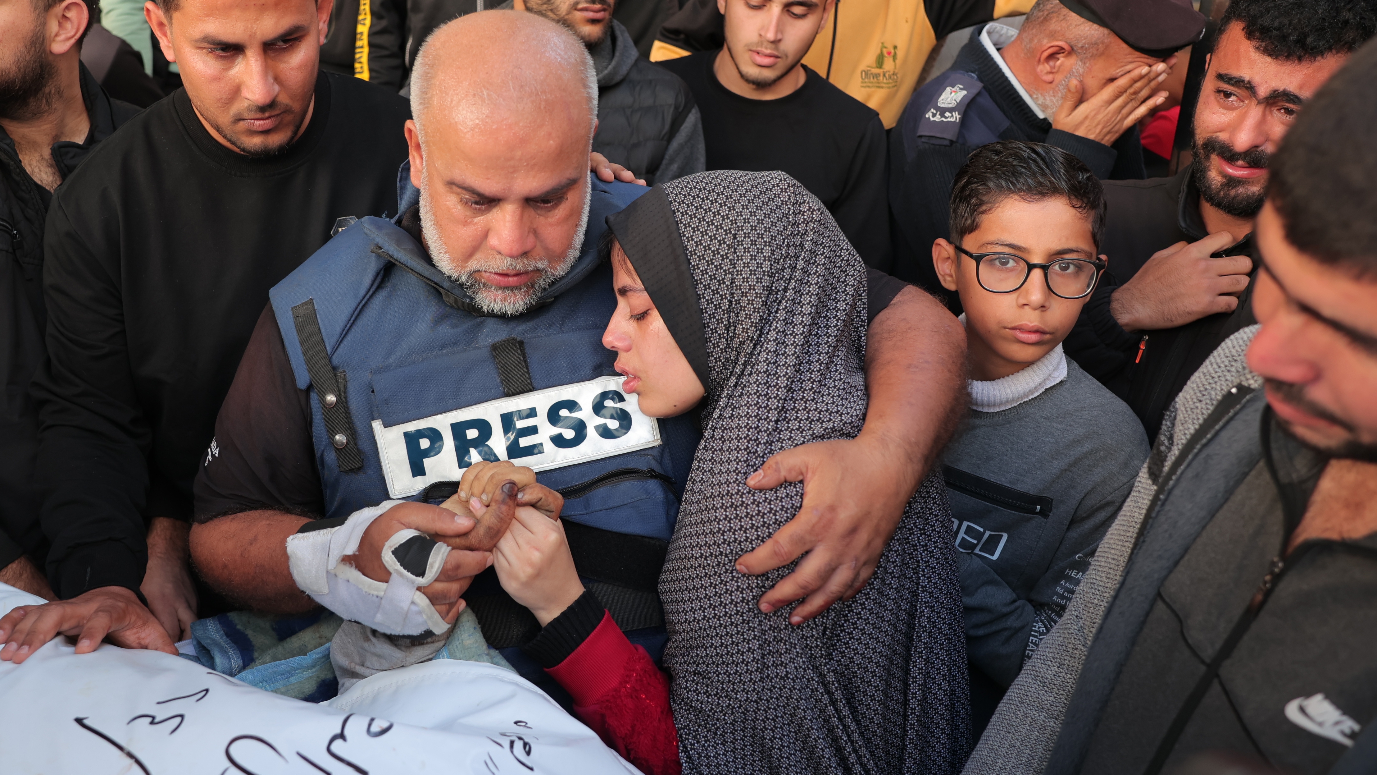 O jornalista da Al Jazeera Wael Al-Dahdouh segura a mão de seu filho Hamza, também informante morto em um ataque israelense, enquanto abraça uma de suas filhas em janeiro passado.