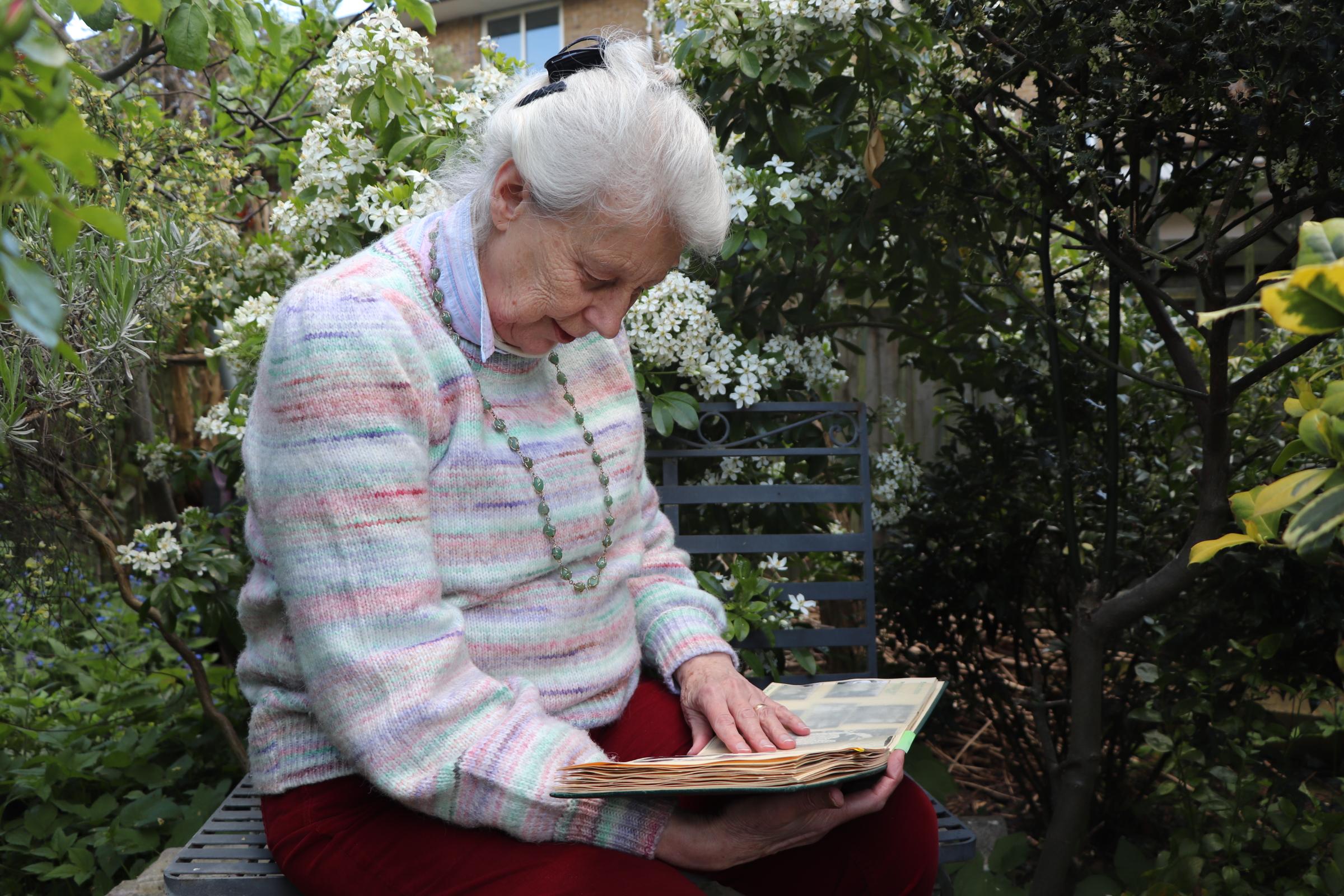 Kathleen Winch, testemunha de duas coroações, folheia seu álbum de fotos em seu jardim no oeste de Londres no domingo.