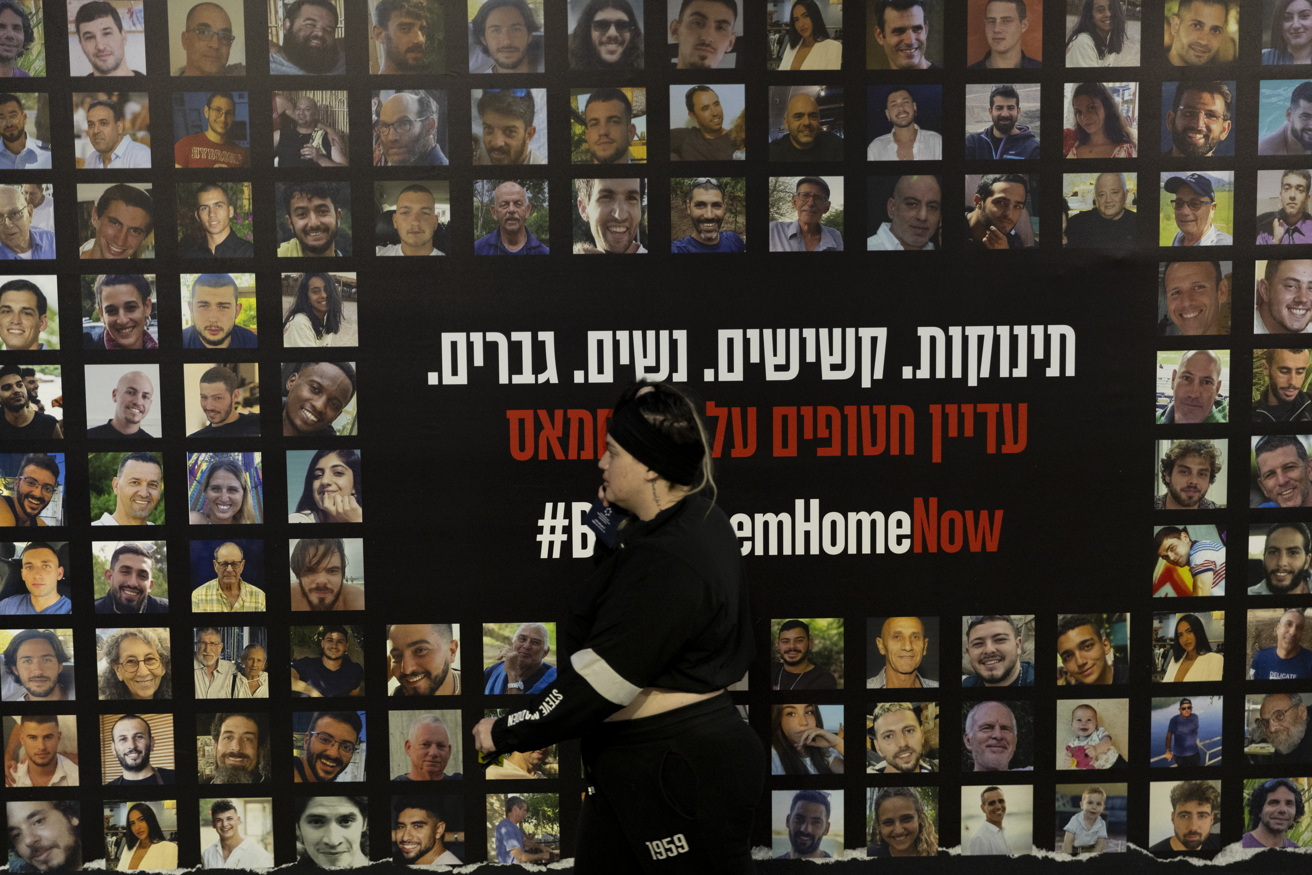 TEL AVIV, ISRAEL - DECEMBER 28: A woman walks by a wall covered with photos of hostages held by Hamas in the Gaza Strip in a train station on December 28, 2024 in Tel Aviv, Israel. Former hostages, family members of hostages, and thousands of their supporters are rallying for a deal to be made with Hamas to return the 100 people who remain captive in Gaza. The Israeli government and Hamas have blamed each other for stalled negotiations, after talks appeared to build momentum in recent weeks. (Photo by Amir Levy/Getty Images)