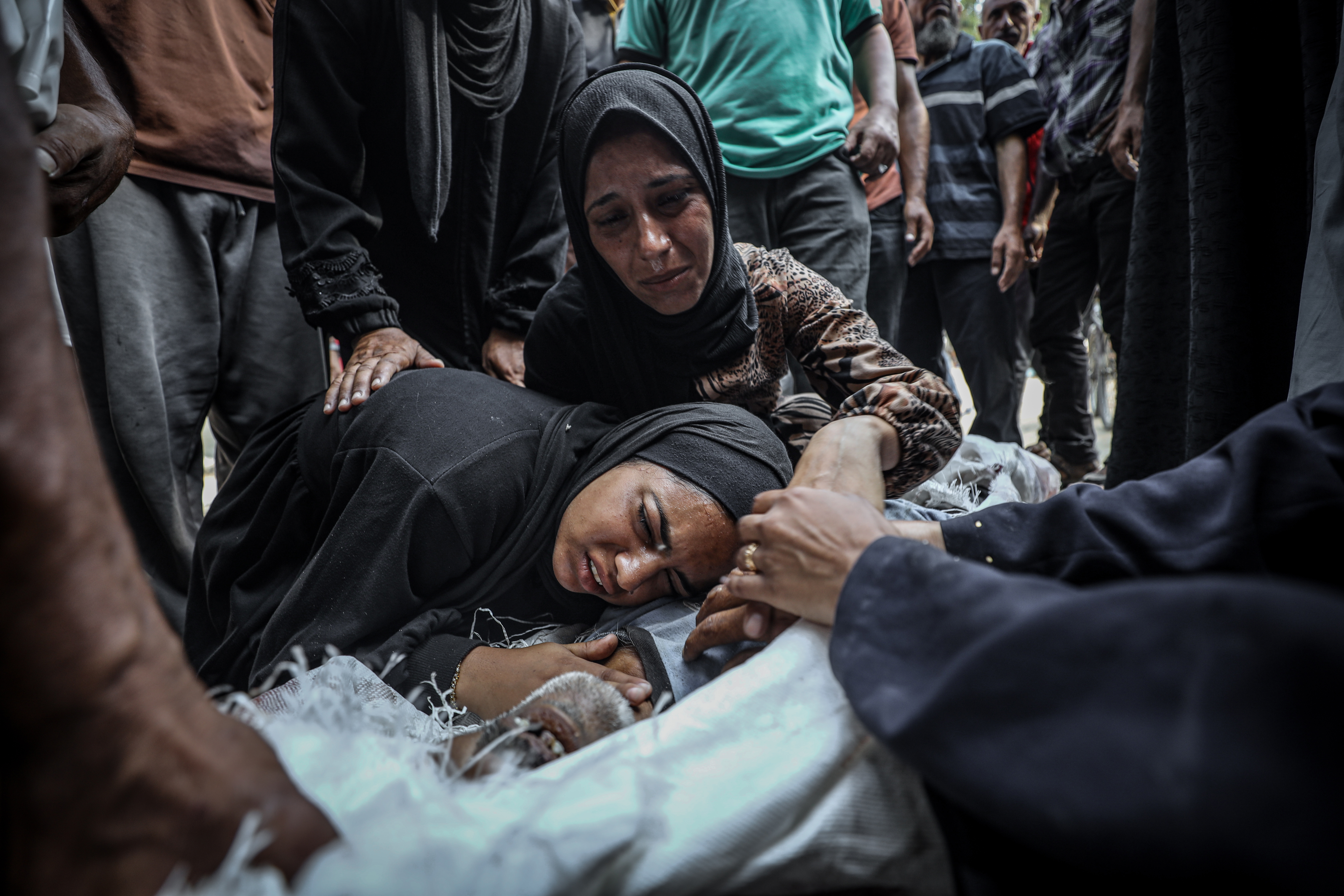 Dos mujeres sobre el cadáver de una persona asesinada por el ejército israelí mientras esperaba la entrega de ayuda humanitaria en el punto de Zikim, en el centro norte de Gaza, este lunes 4 de agosto