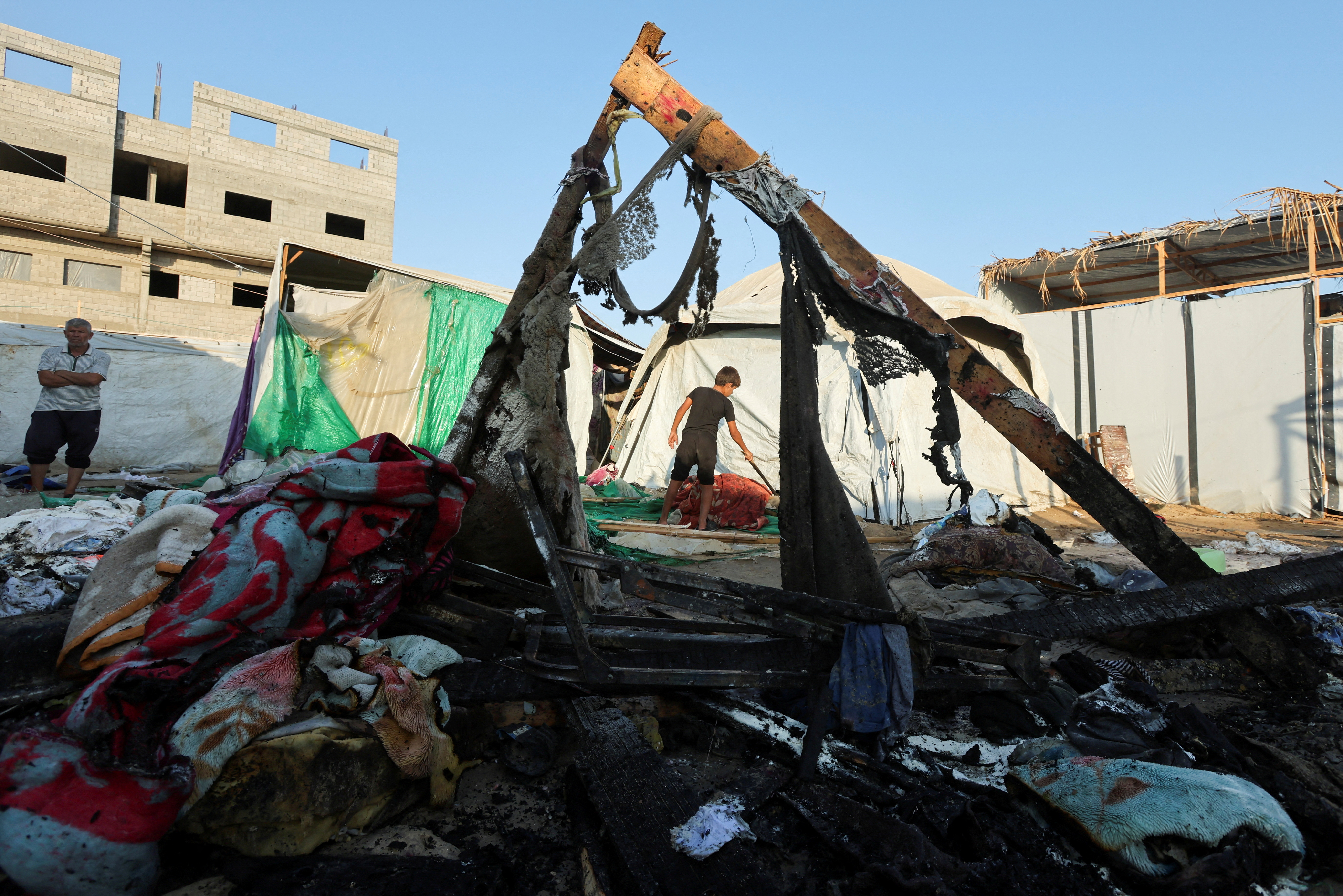 Palestinians inspect the site of an Israeli strike on a tent camp for displaced people, amid the Israel-Hamas conflict, in Deir Al-Balah in the central Gaza Strip, August 4, 2024. REUTERS/Ramadan Abed