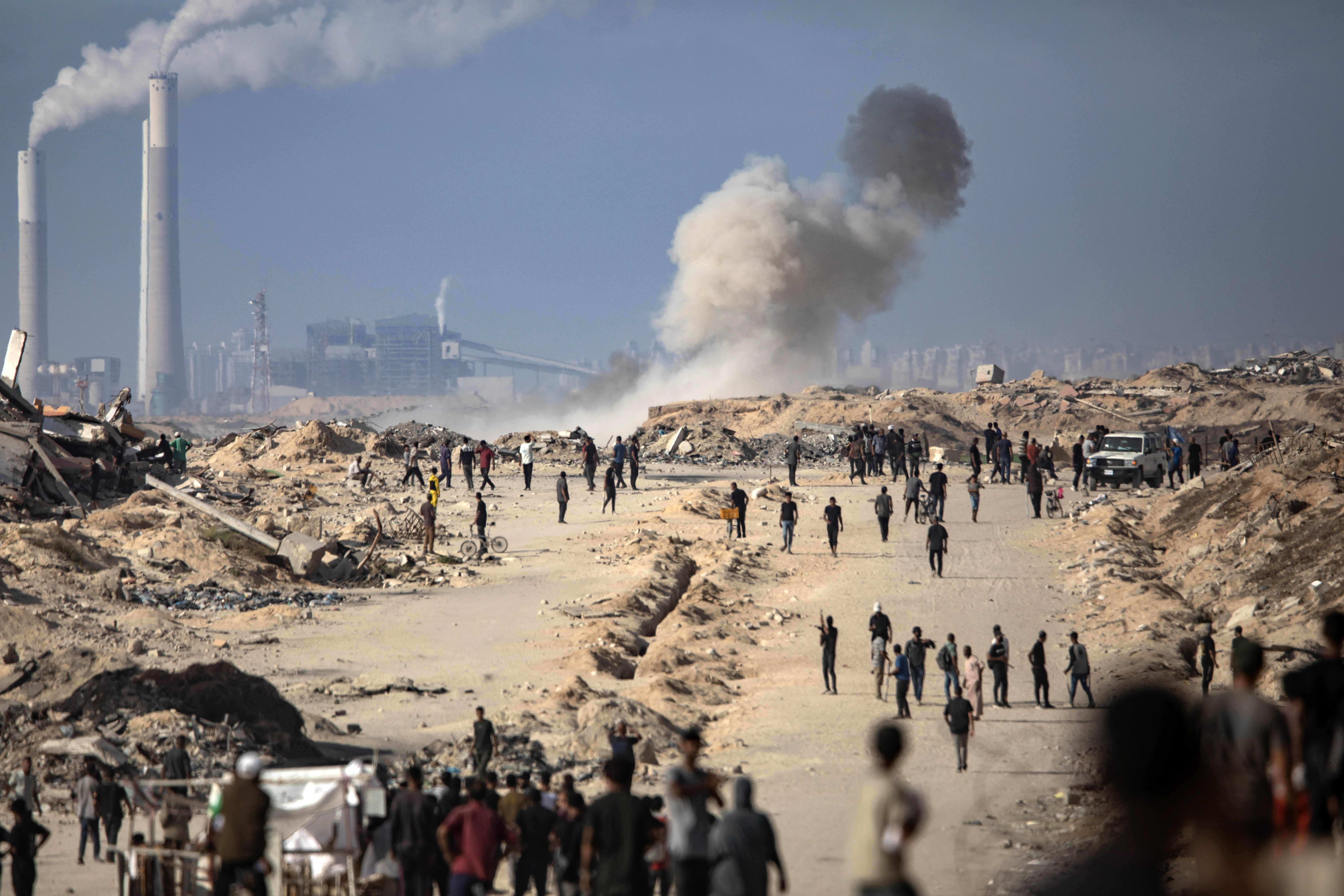 Un tanque israelí dispara junto a gazatíes que se dirigen a un punto de recogida de alimentos, este miércoles al oeste de Ciudad de Gaza.