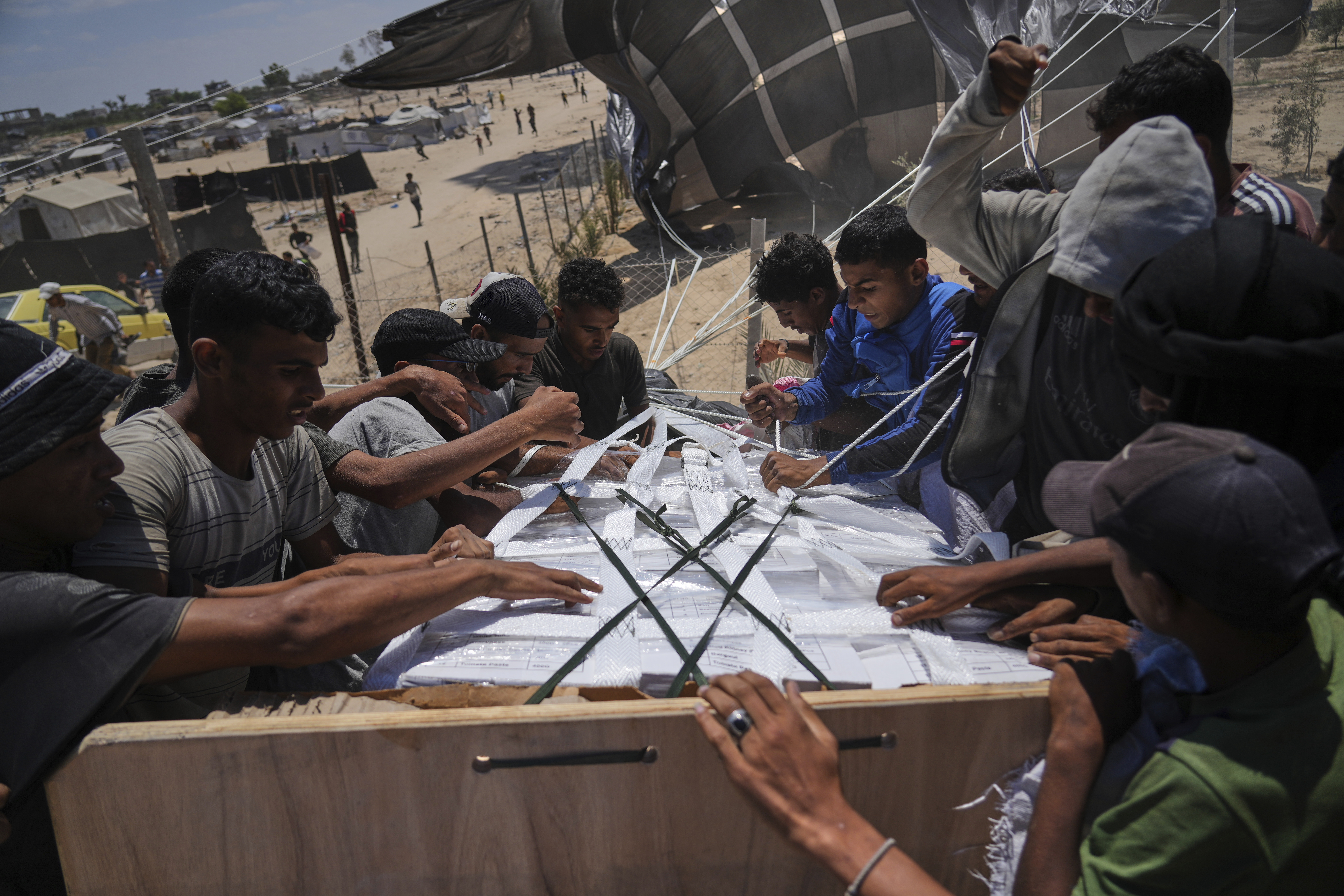 Palestinians open humanitarian aid packages that were airdropped by parachute into Deir al-Balah in central Gaza, Tuesday, Aug. 5, 2025. (AP Photo/Abdel Kareem Hana)