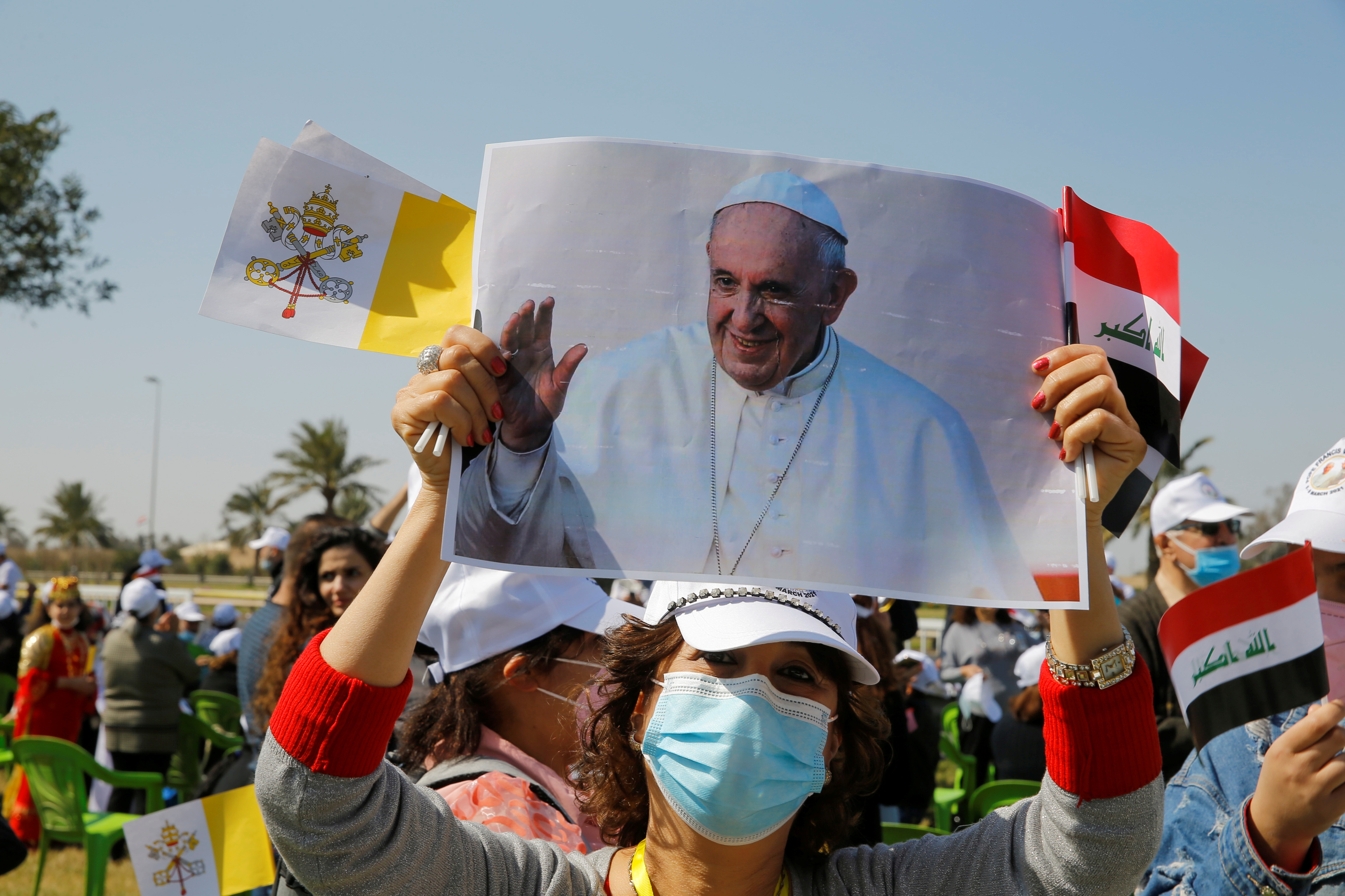 A woman holds a picture of Pope Francis as she waits for his arrival, at Baghdad Airport Road, in Baghdad, Iraq March 5, 2021. REUTERS/Thaier al-Sudani