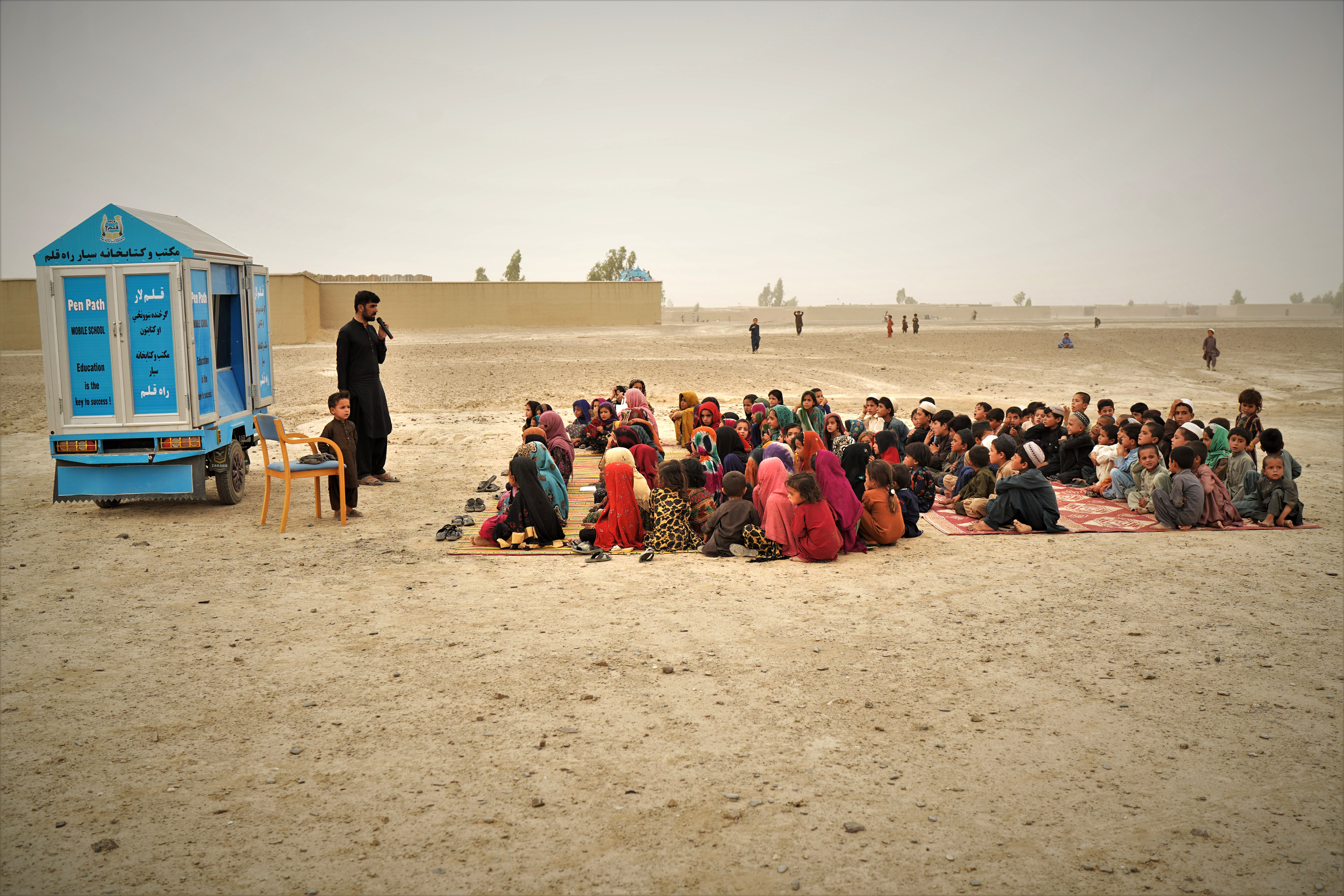 Cem meninas e meninos afegãos de um vilarejo sem escola próximo à fronteira com o Paquistão frequentam aulas graças a uma escola móvel administrada pela ONG Pen Path, no distrito de Spin Boldak, na província de Kandahar, em 11 de agosto de 2022.