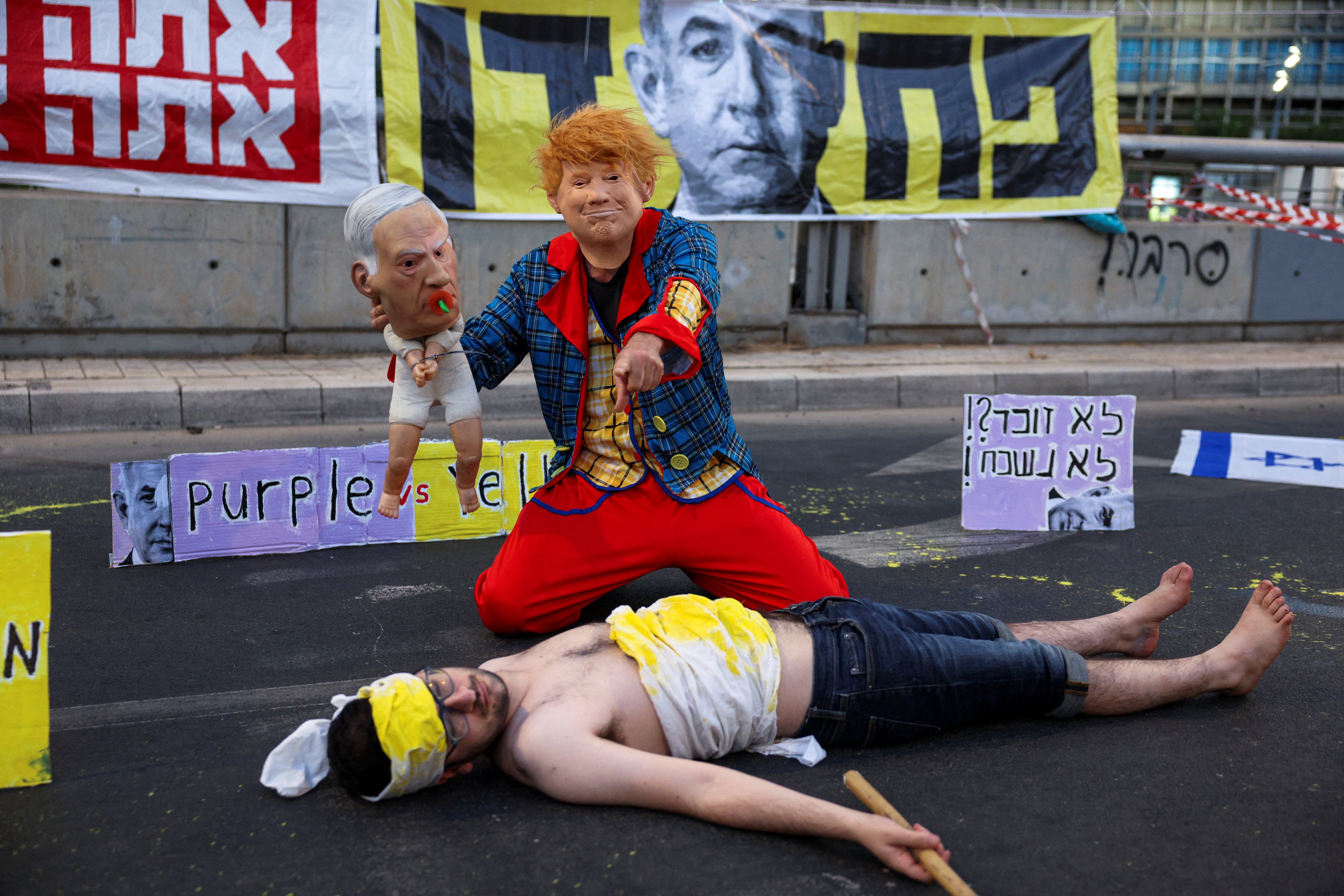 Un manifestante con una máscara de Trump y un muñeco que representa a Netanyahu realiza una 'performance' junto a otro manifestante tirado en el suelo y representando a los rehenes fallecidos en Gaza, durante una protesta en Tel Aviv para exigir un acuerdo con Hamás.