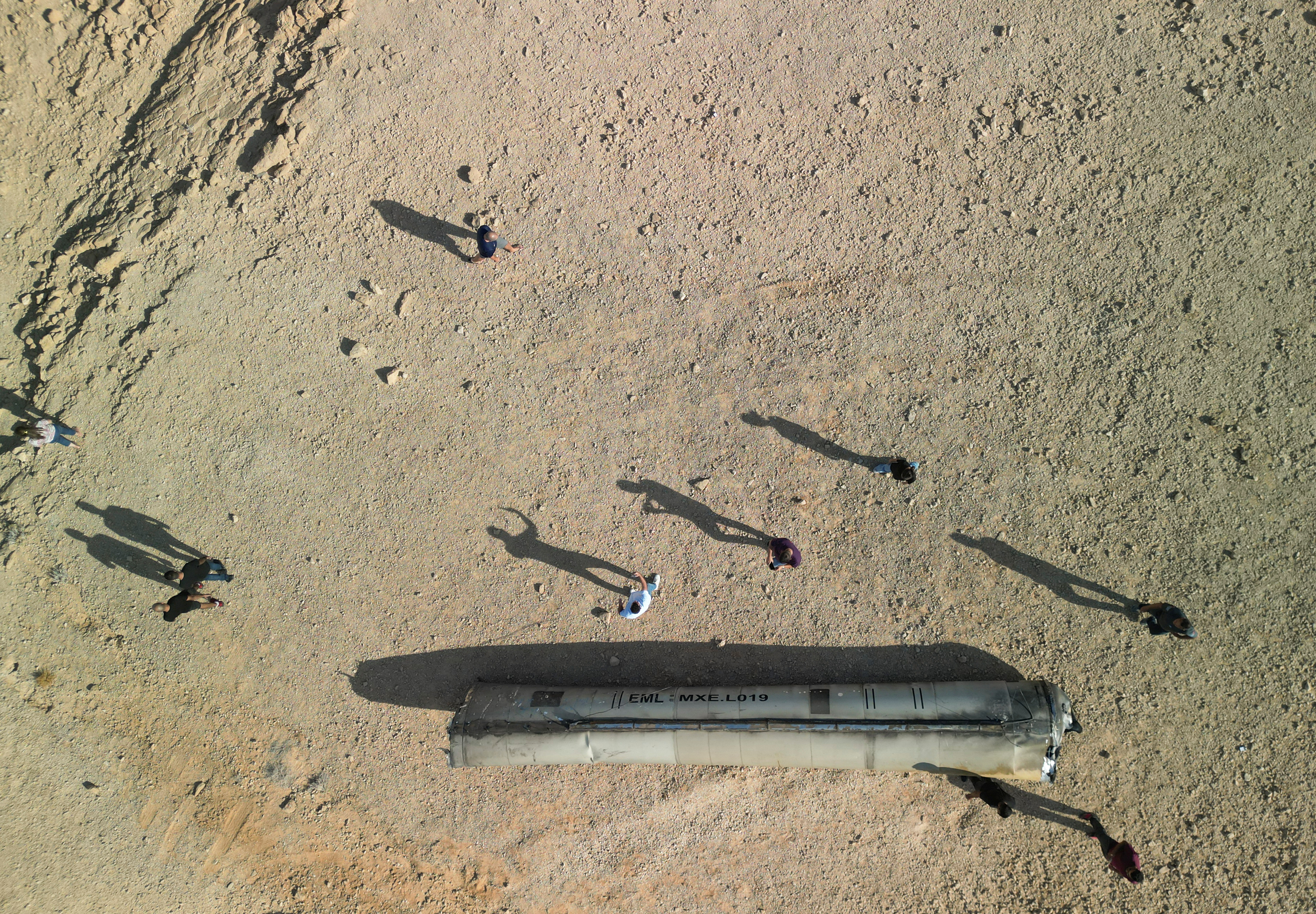 A drone view shows people stand around apparent remains of a ballistic missile lying in the desert, following an attack by Iran on Israel, near the southern city of Arad, Israel October 2, 2024. REUTERS/Amir Cohen