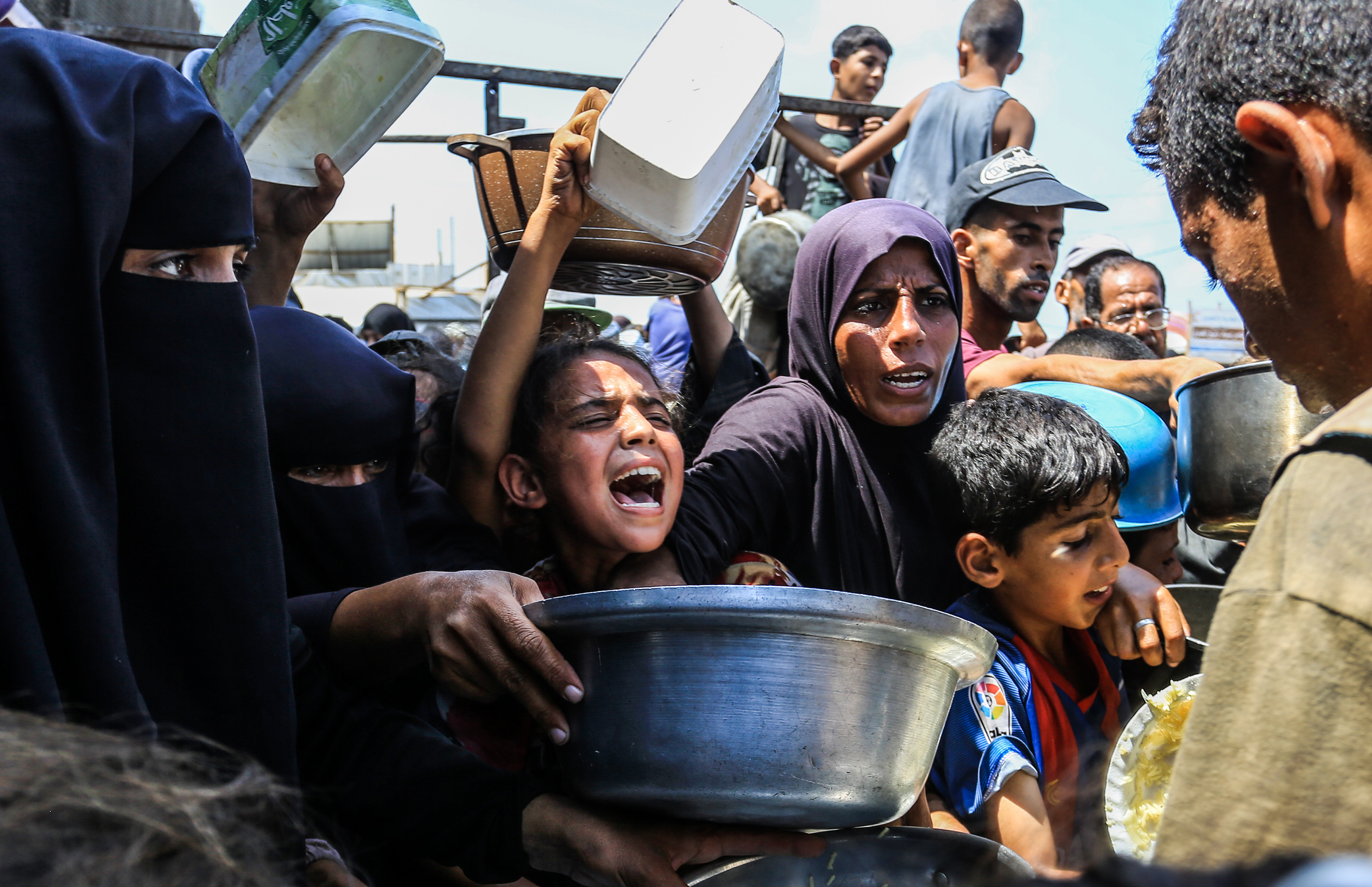 Un grupo de personas intenta conseguir comida en una cocina comunitaria en Jan Yunis, en el sur de la Franja,  el 21 de agosto de 2025.