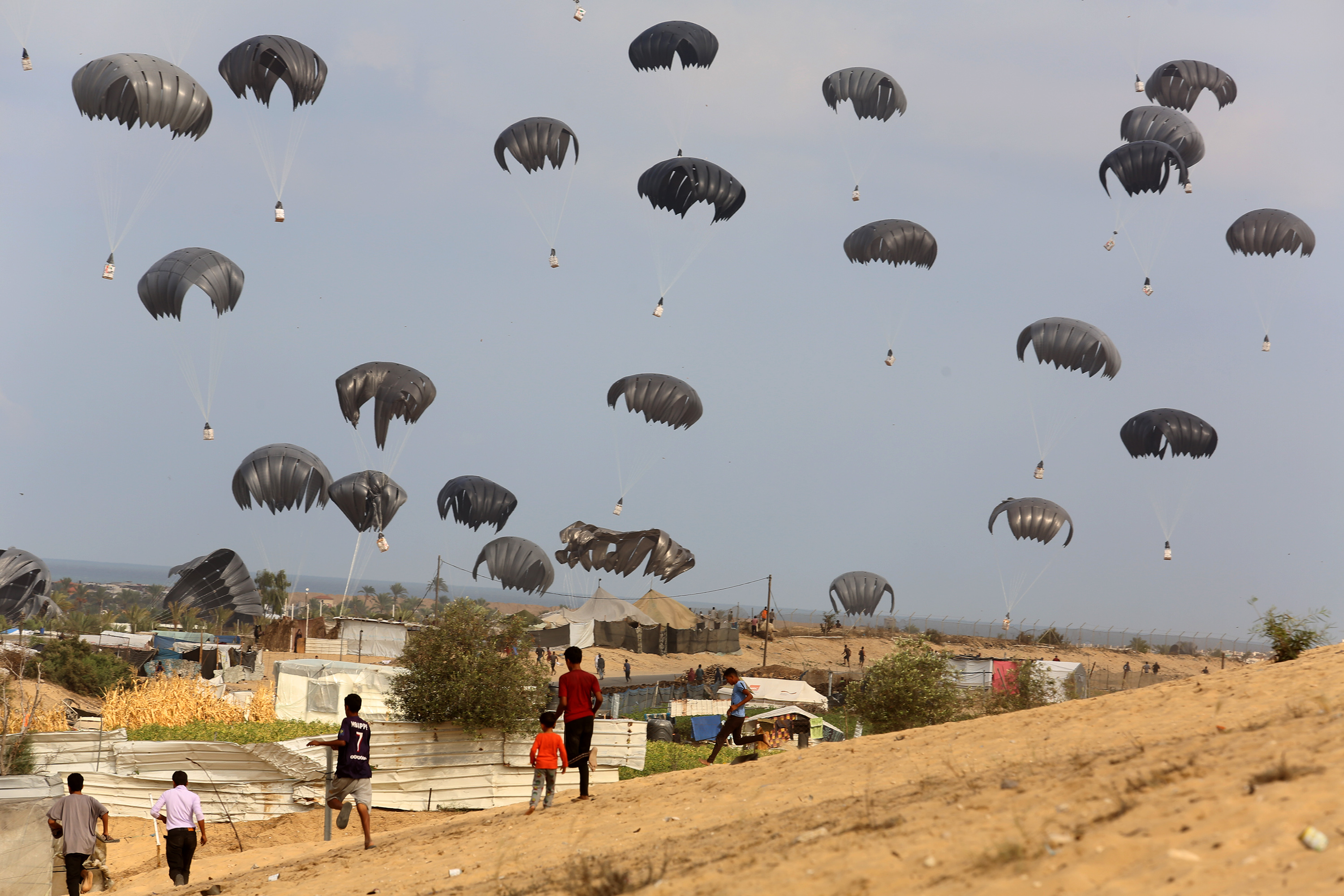 KHAN YUNIS, GAZA - OCTOBER 17: Humanitarian aid packages dropped from planes are seen landing by parachute at Al-Mawasi area as Israeli attacks continue in Khan Yunis, Gaza on October 17, 2024. (Photo by Abed Rahim Khatib/Anadolu via Getty Images)