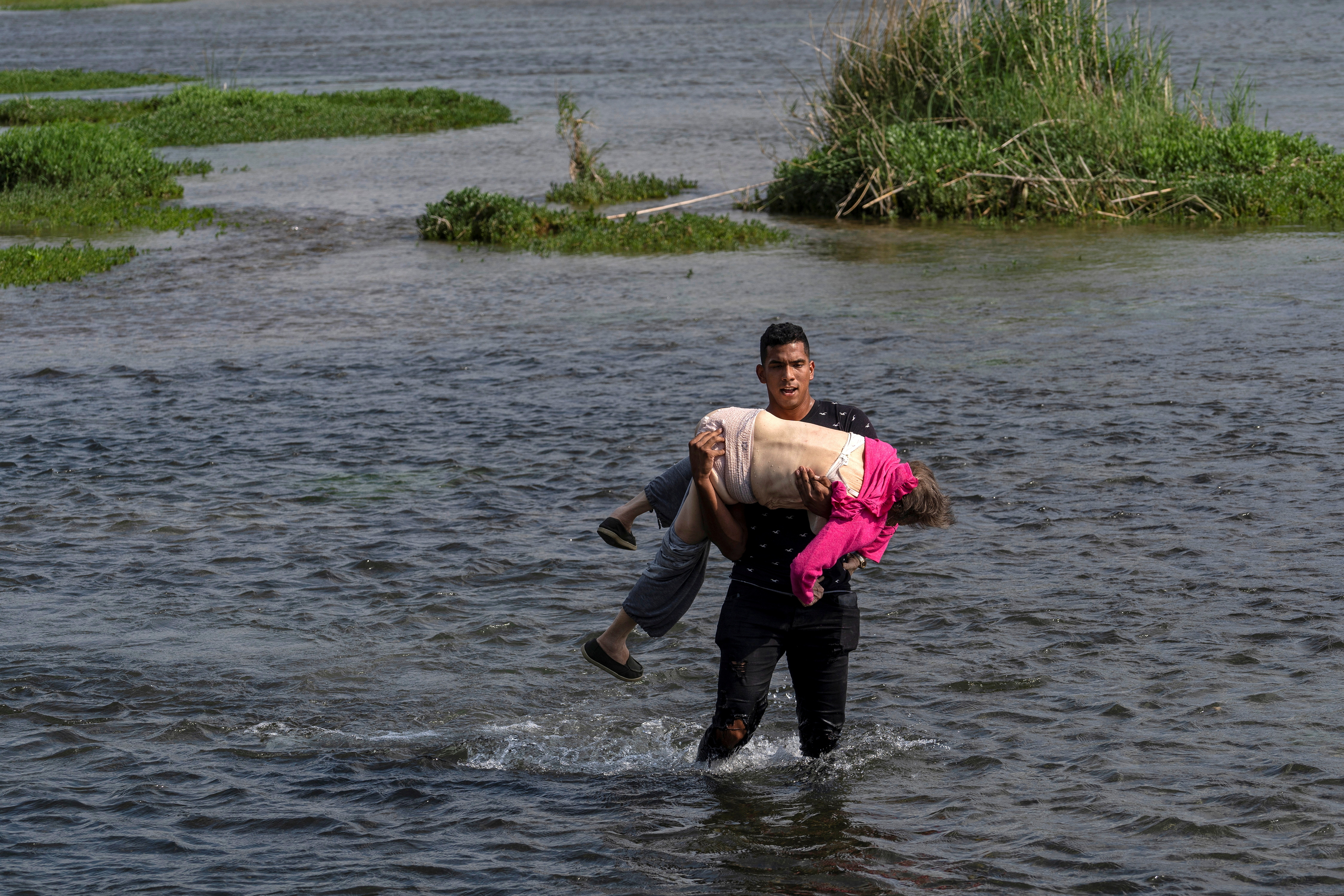 Uma idosa venezuelana cruzando o rio nos braços de outro migrante: a imagem de duas crises intermináveis