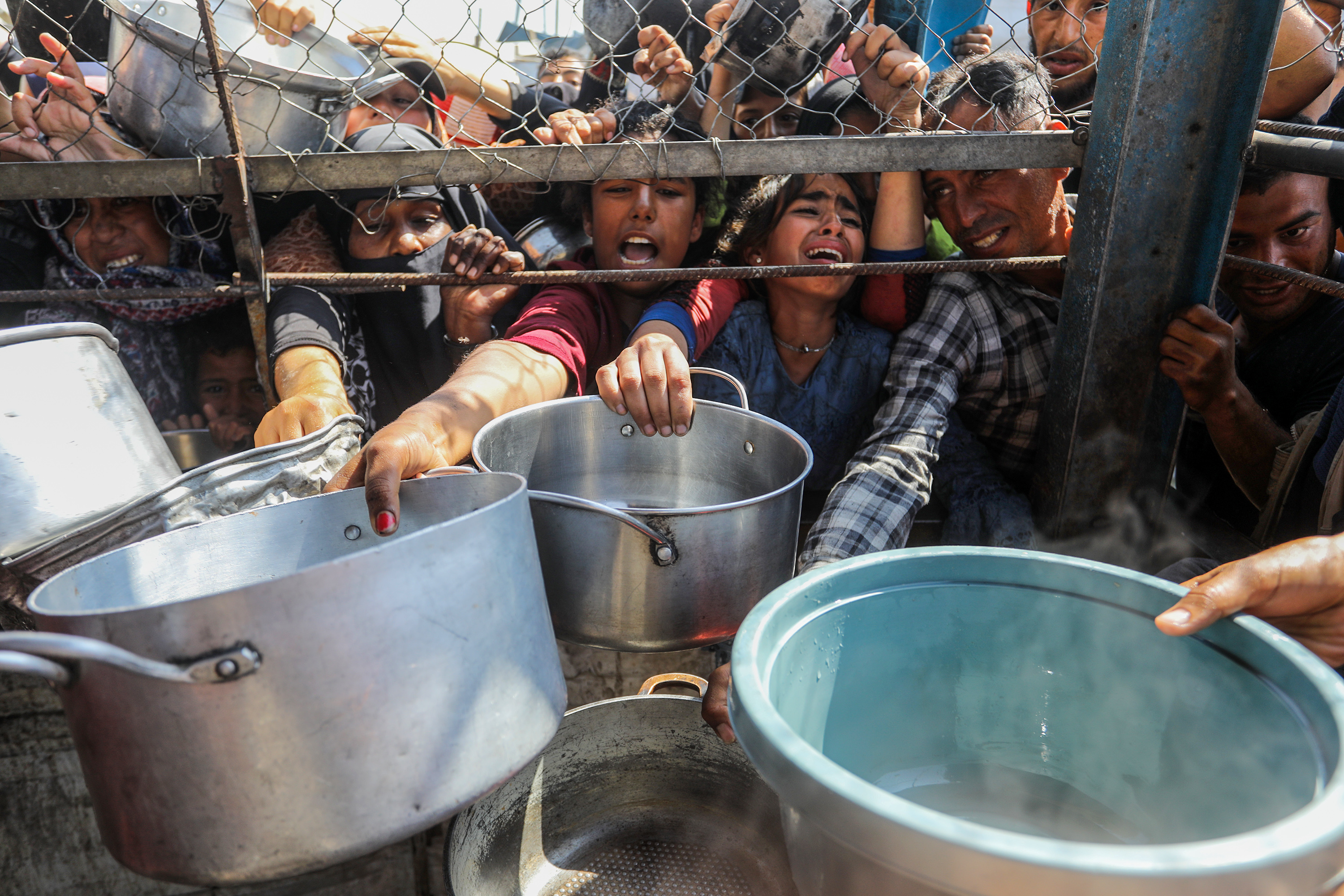 Un grupo de personas intenta conseguir comida en una cocina comunitaria en Jan Yunis, al sur de la Franja, este jueves 5 de junio.