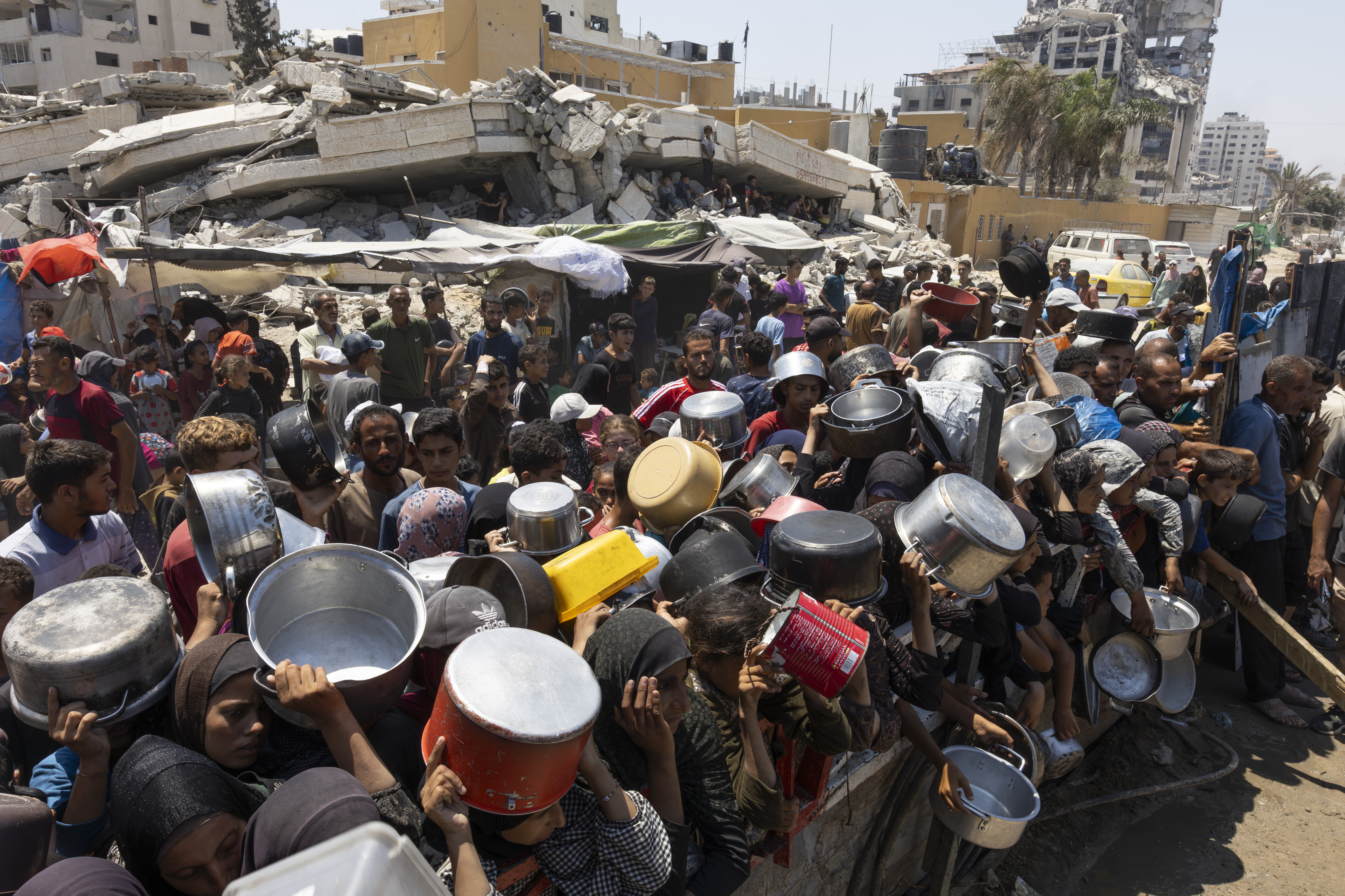 GAZA CITY, GAZA - JULY 25: Hundreds of Palestinians struggling with hunger wait for hours under the scorching heat to receive food aid distributed by a charity organization as the deepening humanitarian crisis continue to severely impact Palestinians through widespread food shortages in Rimal neighborhood, Gaza on July 25, 2025. (Photo by Mahmoud Abu Hamda/Anadolu via Getty Images)
