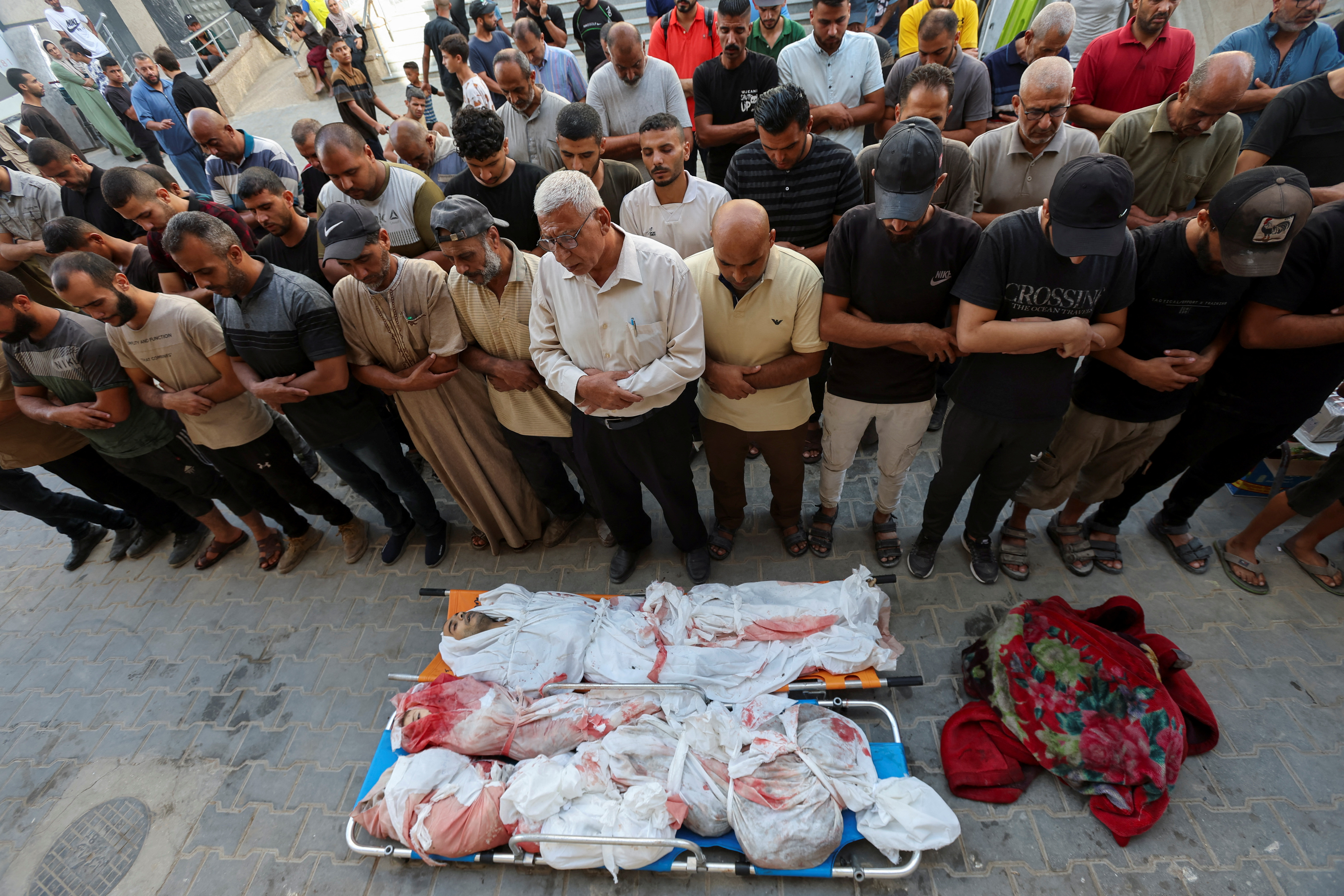  SENSITIVE MATERIAL. THIS IMAGE MAY OFFEND OR DISTURB    Mourners pray next to the bodies of Palestinians killed in Israeli strikes, amid the Israel-Hamas conflict, at Al-Aqsa Martyrs Hospital in Deir Al-Balah in the central Gaza Strip, September 16, 2024. REUTERS/Ramadan Abed