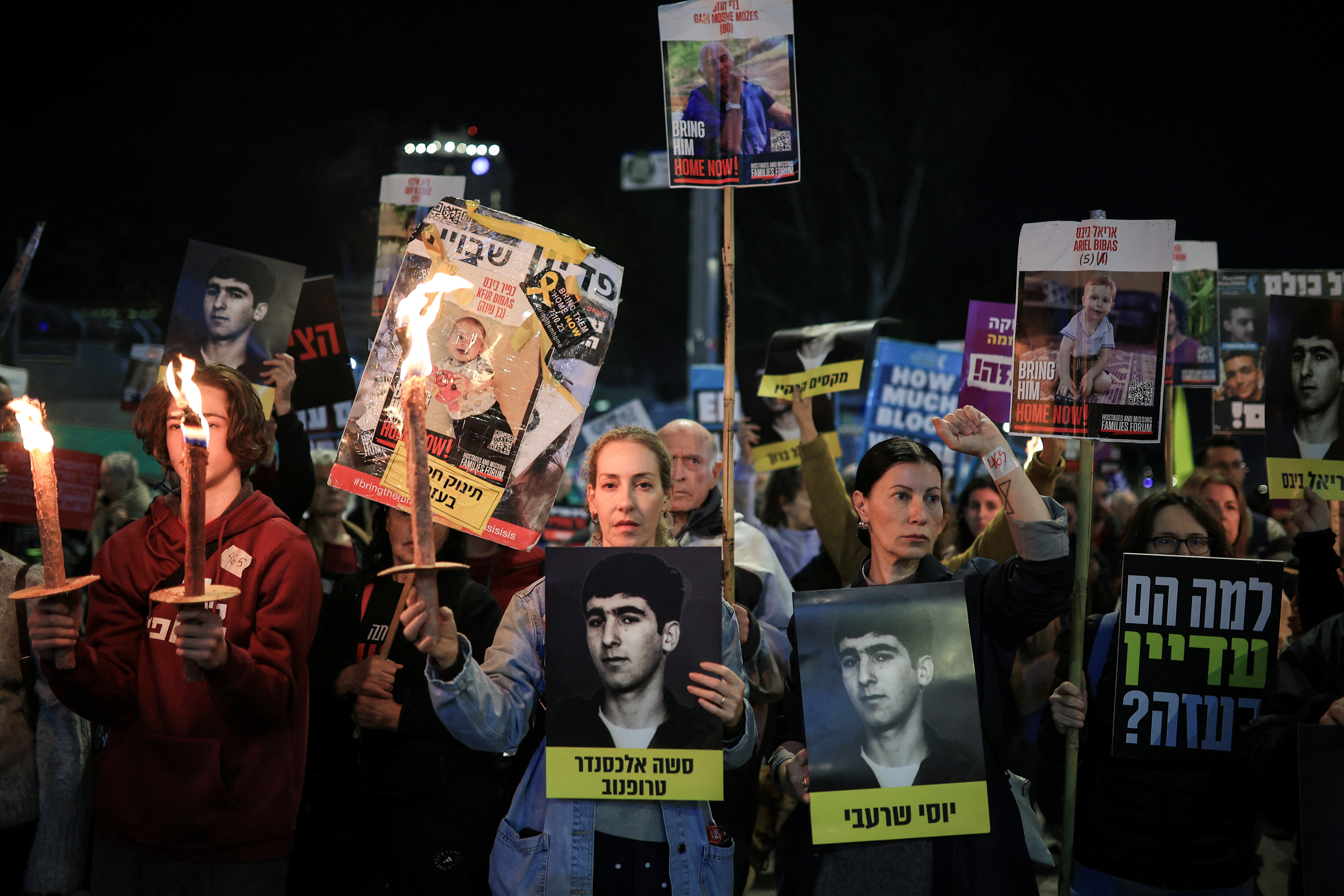 Manifestantes sostienen fotografías de los rehenes israelíes, mientras exigen un acuerdo durante una protesta este lunes en Tel Aviv.