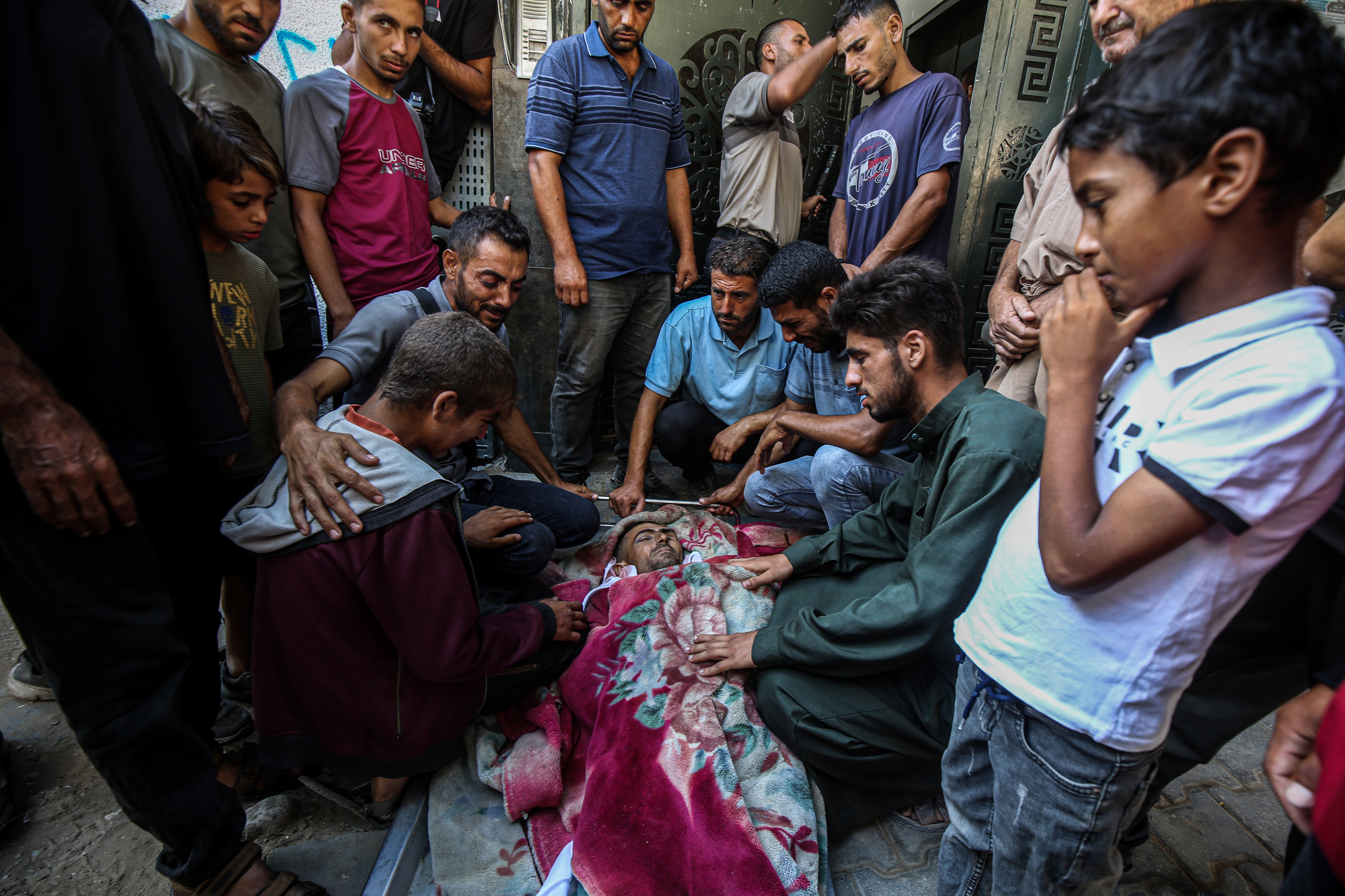 Un grupo de personas alrededor del cuerpo de uno de los palestinos asesinados mientras intentaba conseguir alimento, en el hospital Al Shifa, en el centro de la Franja, este martes 5 de agosto.