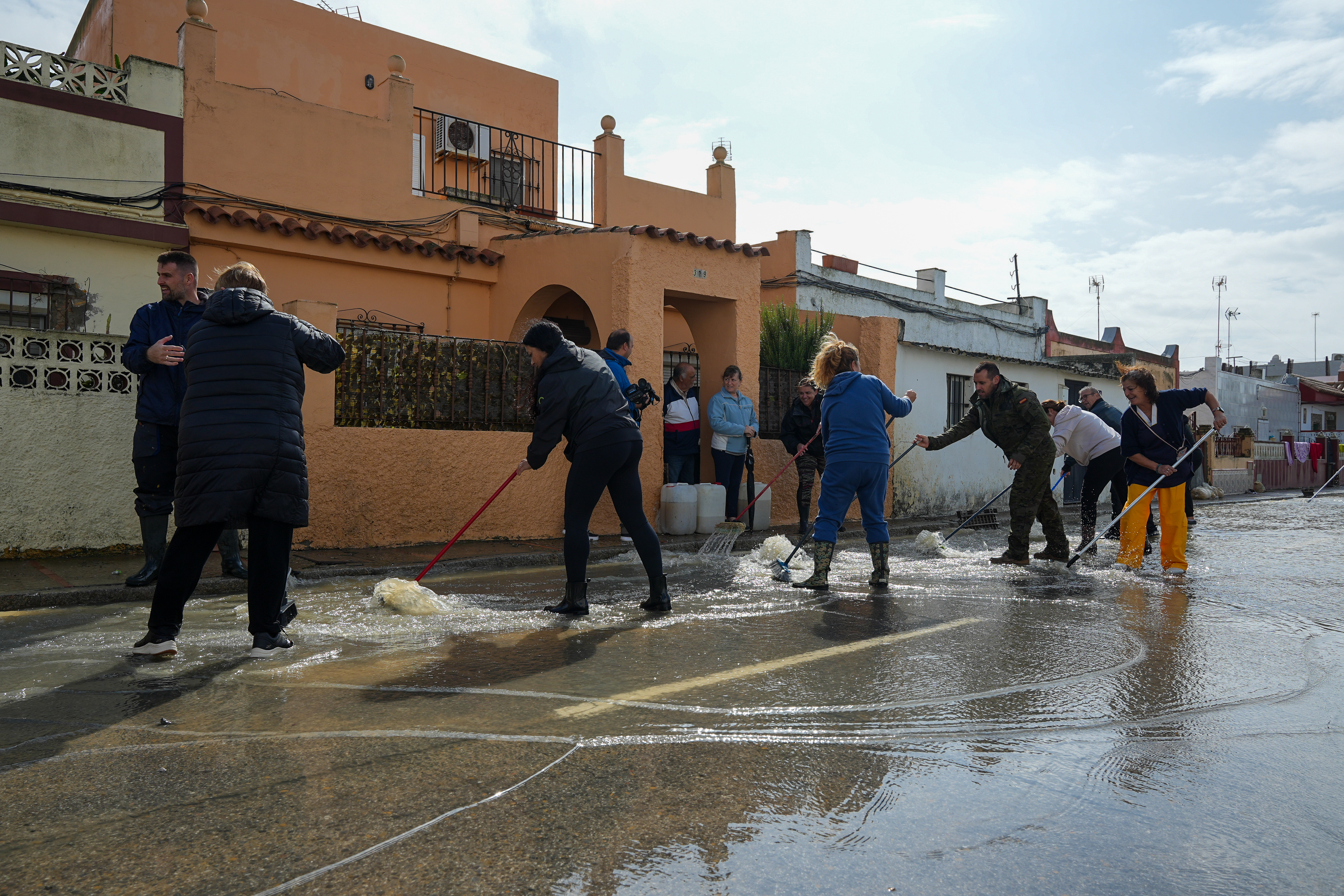 Vecinos de la calle Buen Pastor, en San Fernando (Cádiz), barren el agua a la alcantarilla, este 31 de octubre