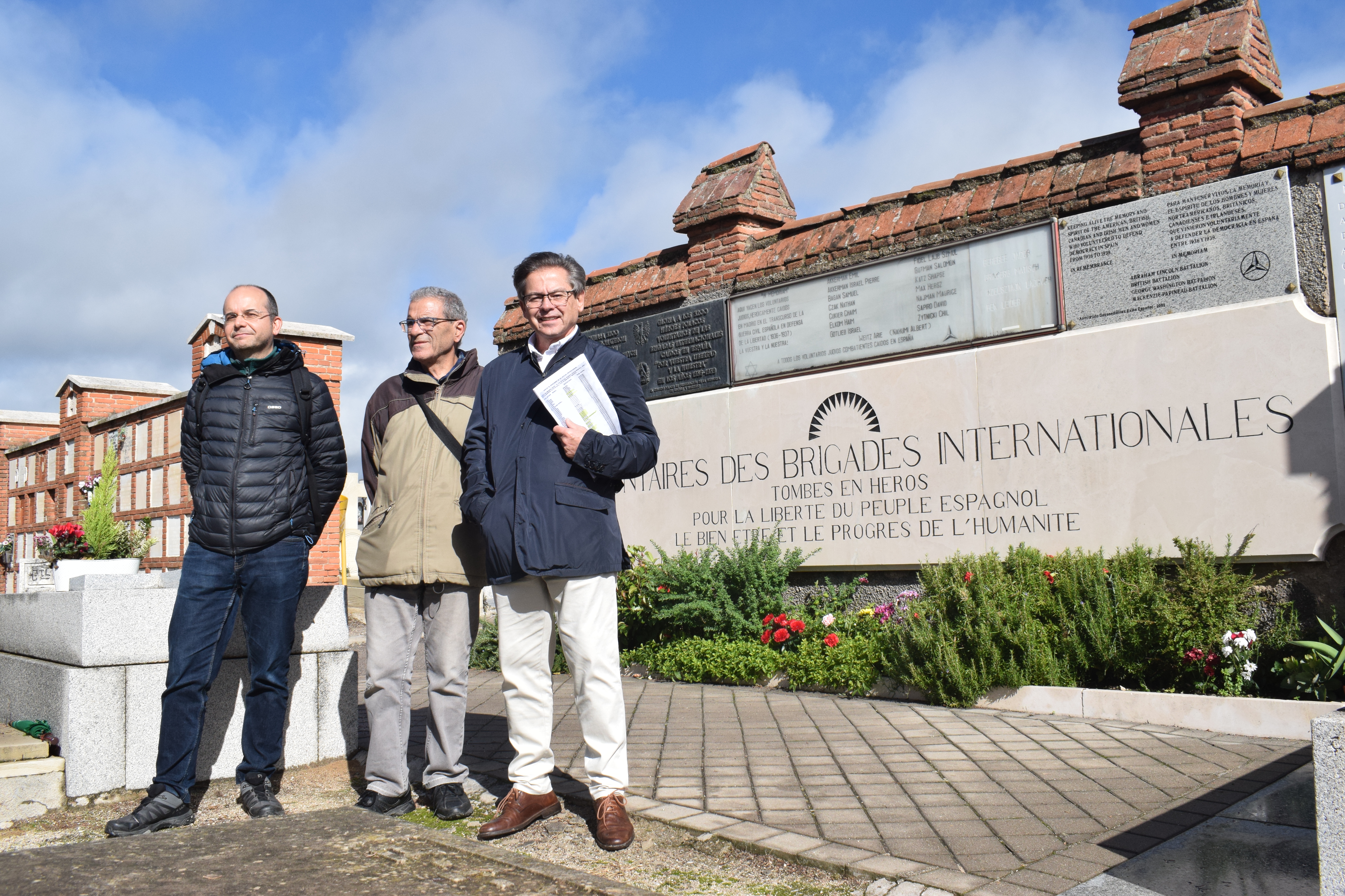 Andrés Chamorro y Severiano Montero, de la Asociación de Amigos de los Brigadistas Internacionales, y Luis González, el vecino del barrio, frente a la placa del cementerio de Fuencarral.