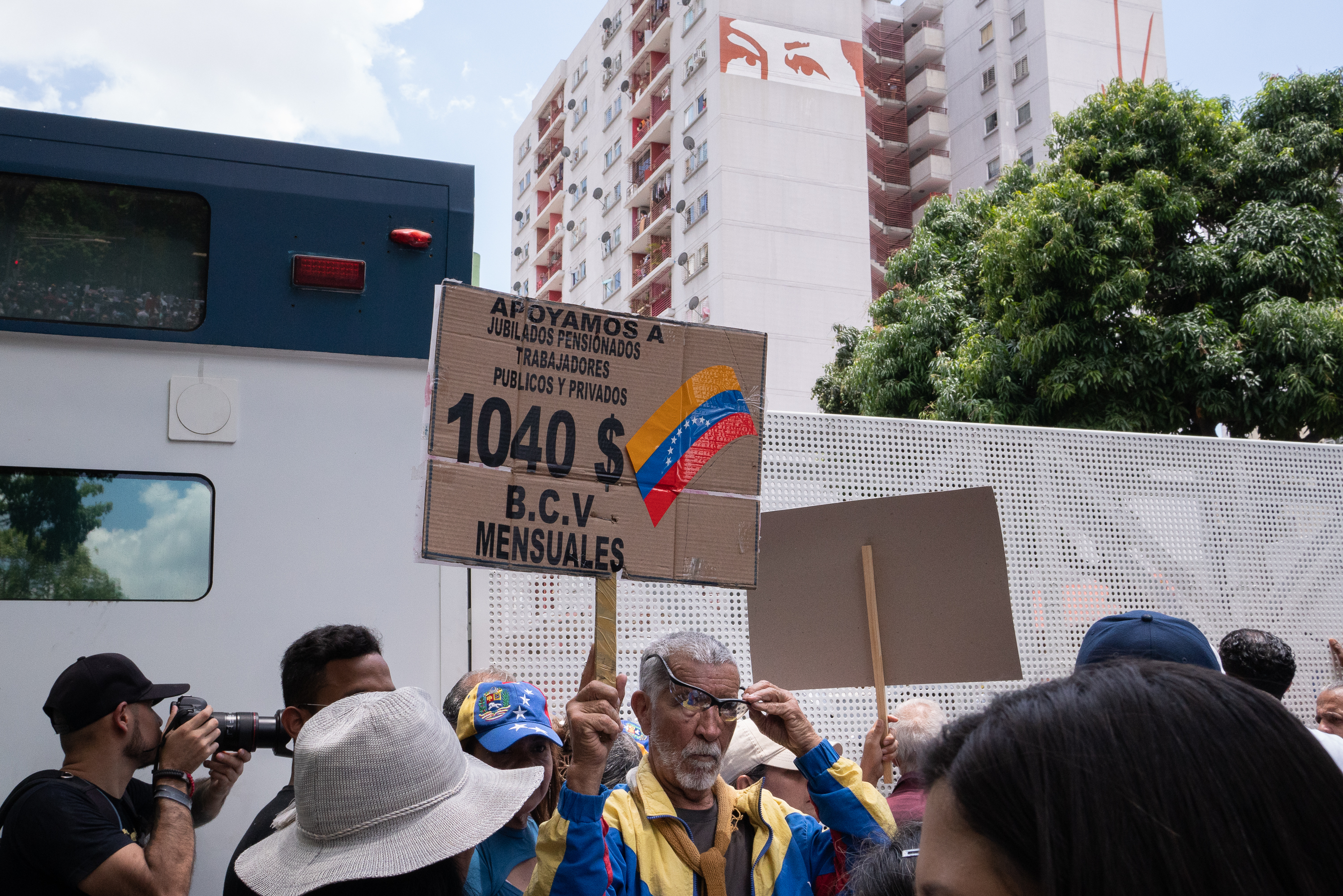 Um manifestante aposentado segura sua placa na frente de um caminhão de choque.