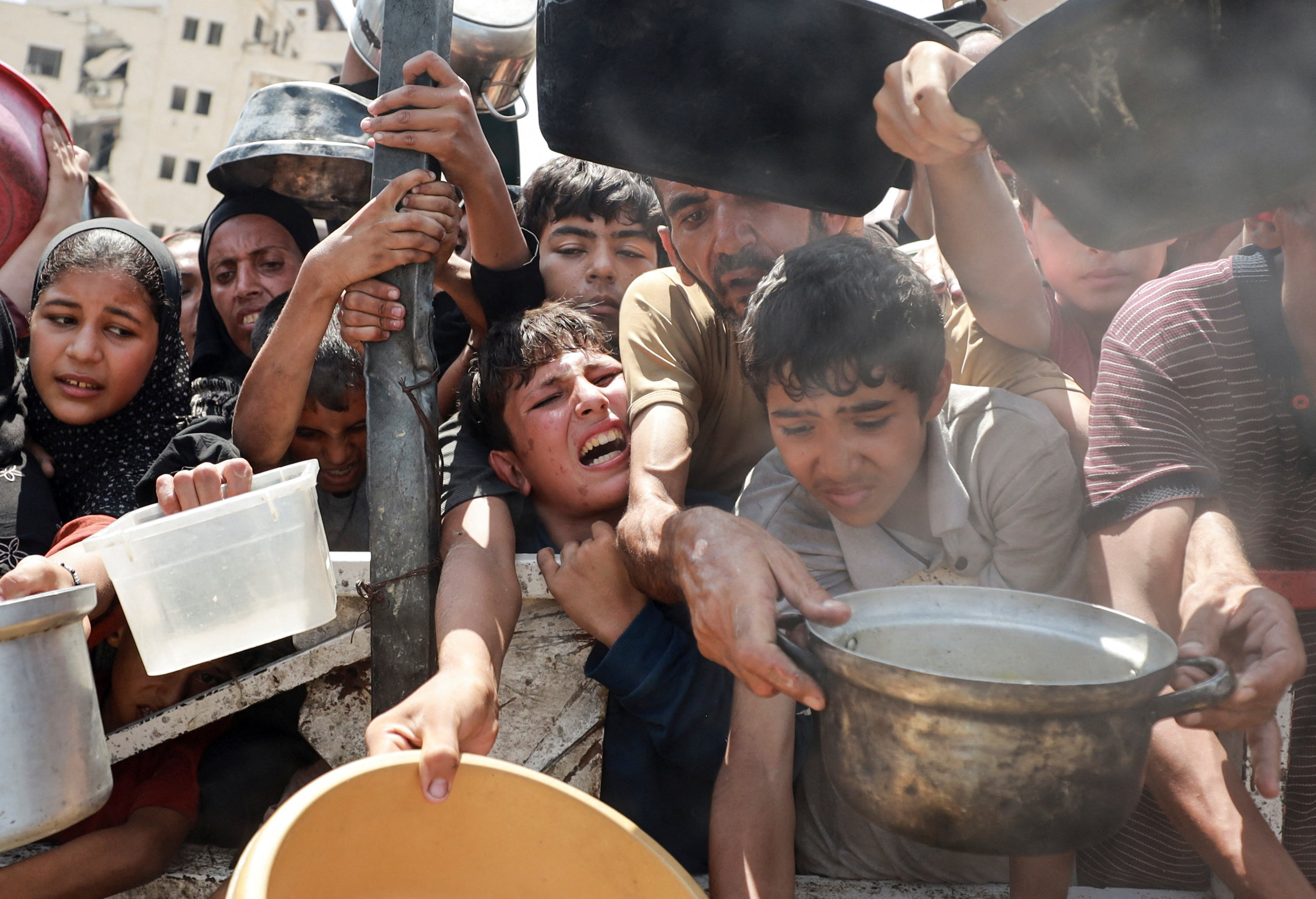 Un grupo de palestinos intenta recibir comida en una cocina comunitaria en Ciudad de Gaza, en el norte del enclave, este lunes 28 de julio.