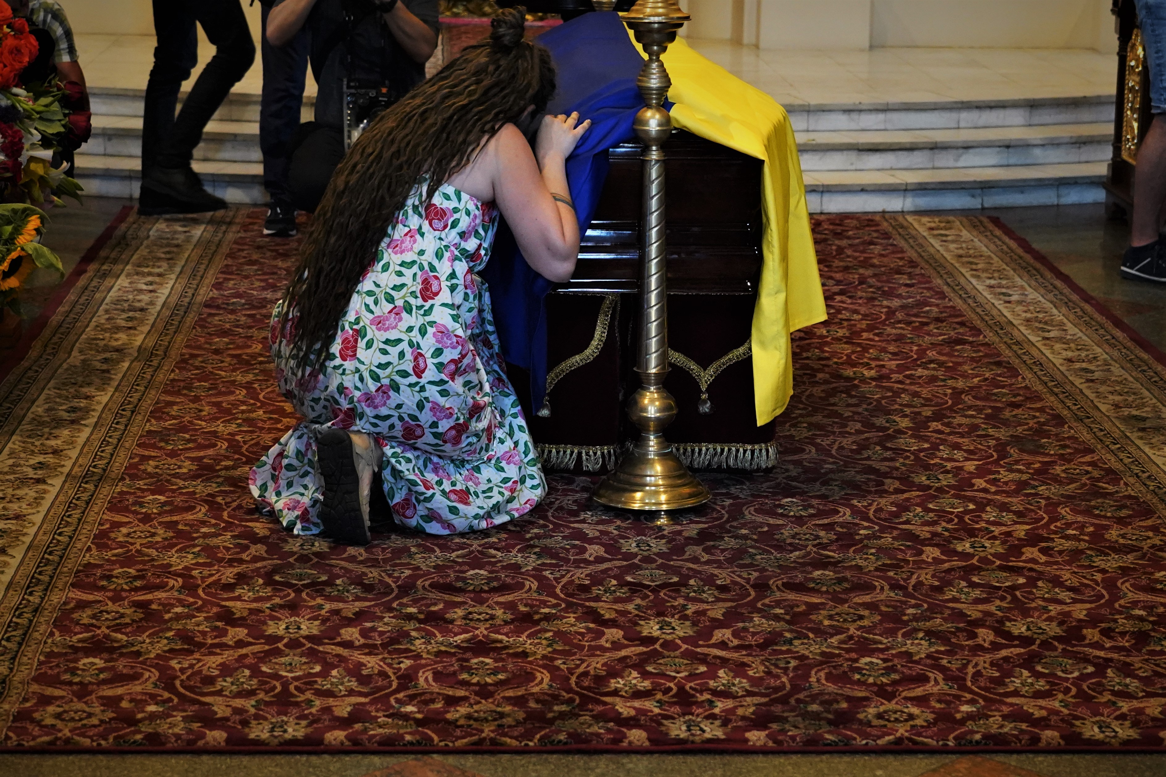 Uma mulher abraça o caixão da escritora ucraniana Victoria Amelina, em seu funeral na terça-feira em Kiev, na Ucrânia.