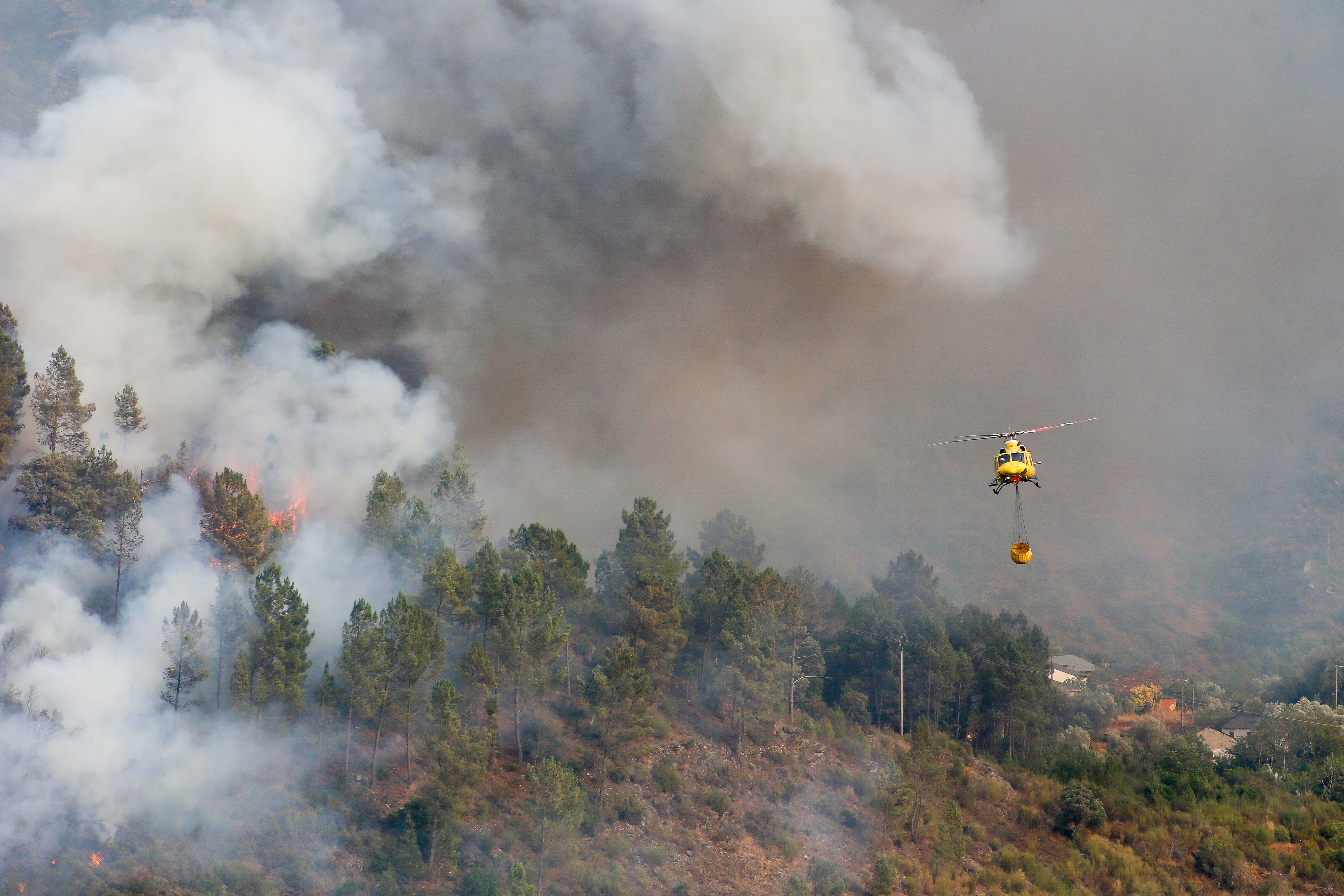 Un helicóptero con un tanque de agua trabaja para extinguir el fuego en Galicia, el 17 de agosto de 2025. 