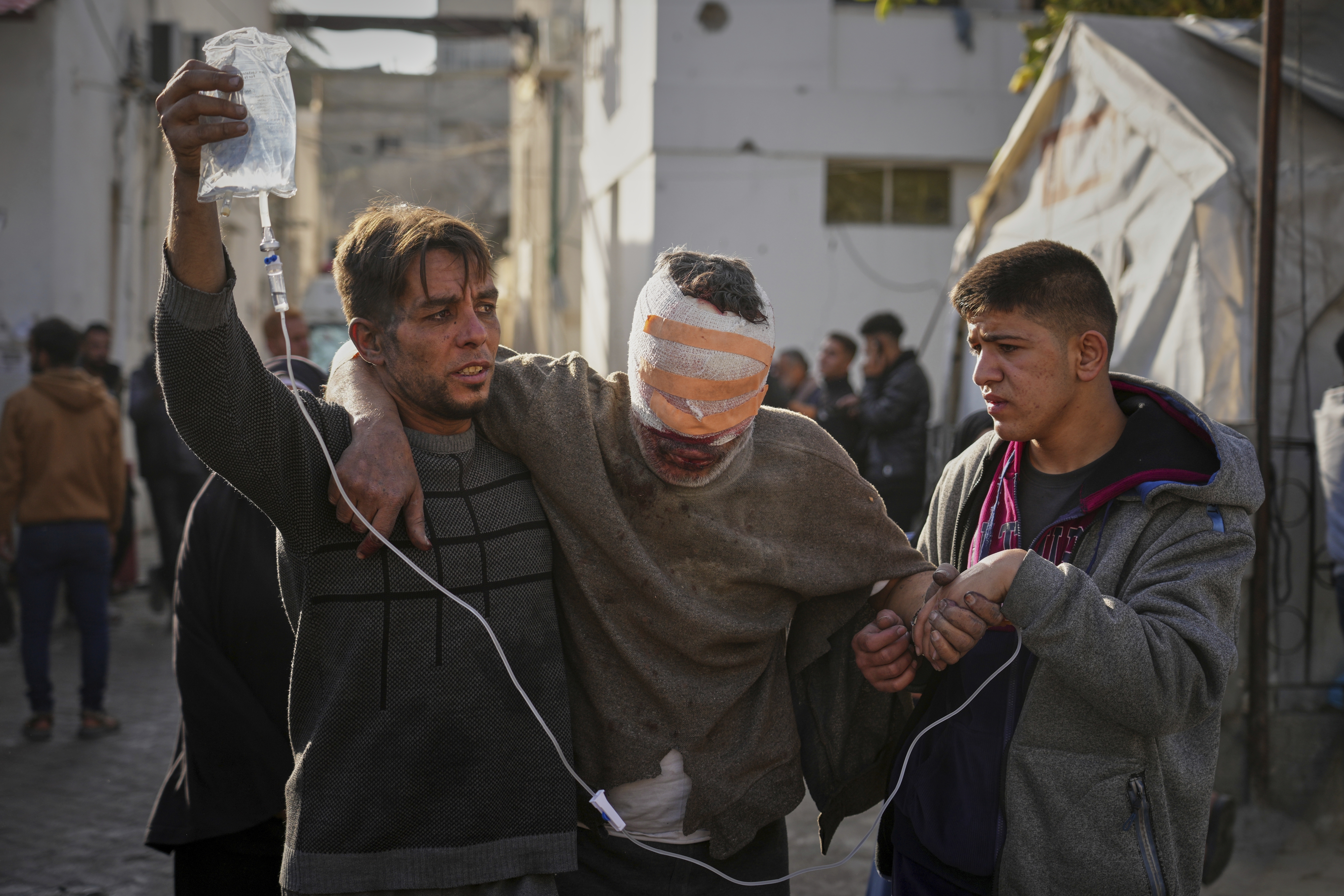 Un hombre herido es trasladado por otros dos al hospital  Al-Ahli tras los ataques israelíes, en Ciudad de Gaza. 