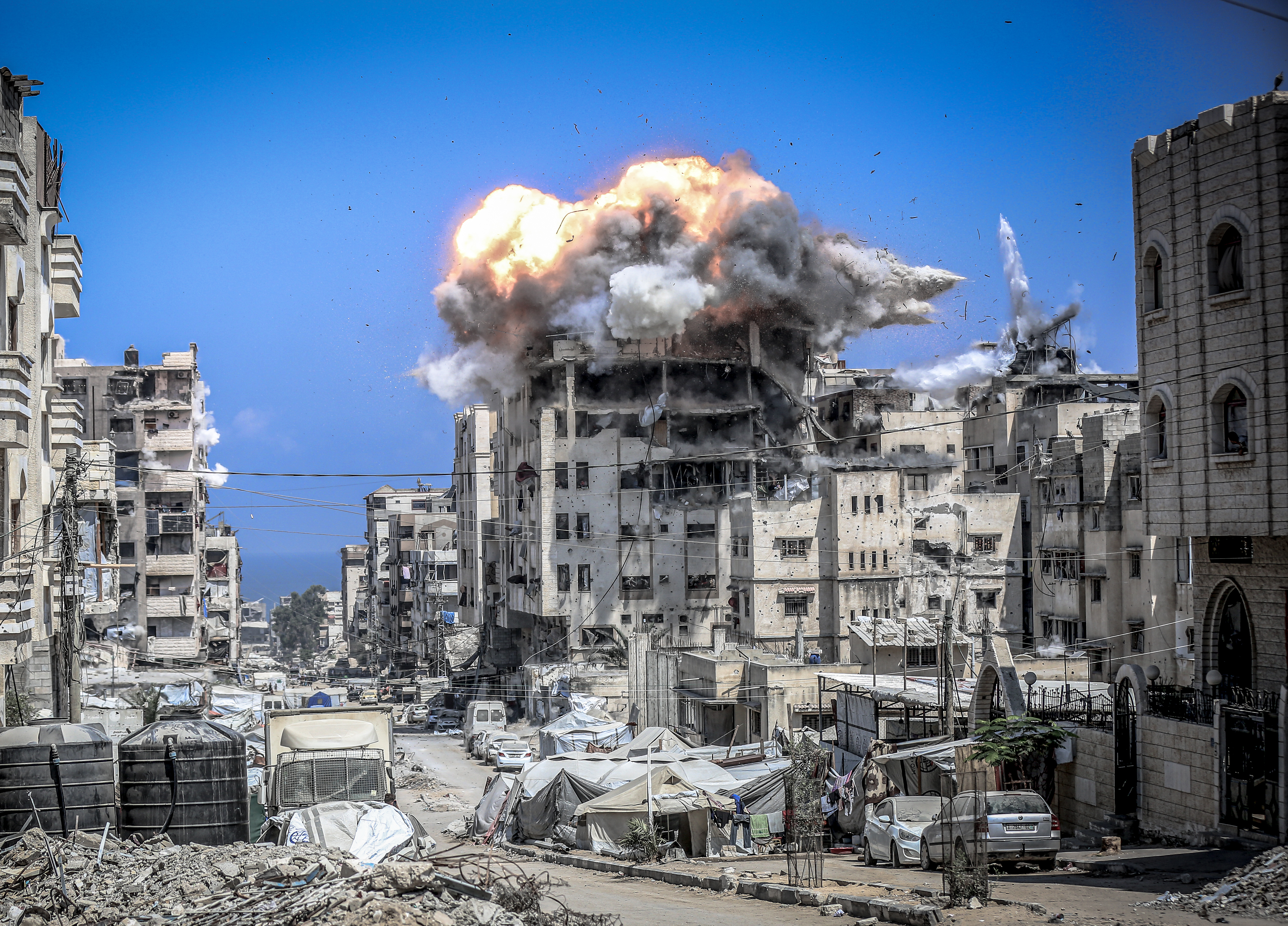 GAZA CITY, GAZA - JULY 21: Thousands of displaced Palestinians who had taken shelter in the building evacuate shortly before the Israeli warplanes targeted the Mehran building located in the Al-Nasr neighborhood in central Gaza, following a warning phone call from the Israeli army in Gaza City, Gaza on July 21, 2025. Smoke billowed from the area during the attack and the school was heavily destroyed after the attack. (Photo by Saeed M. M. T. Jaras/Anadolu via Getty Images)