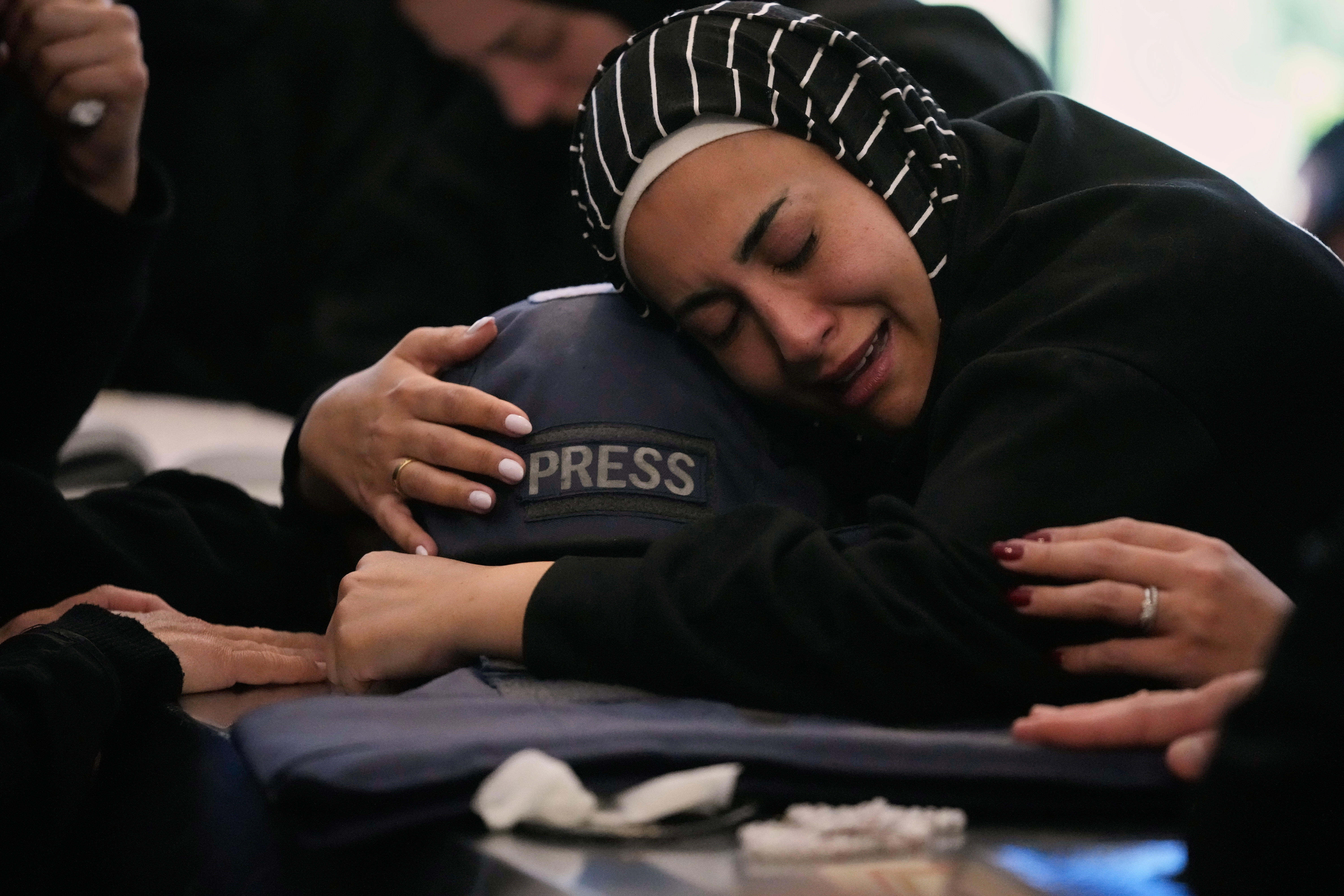 Zainab abraza el casco de su hermana, la periodista Amal Khalil, durante su funeral en Baysariyeh, sur del Líbano. (AP/Mohammed Zaatari) 